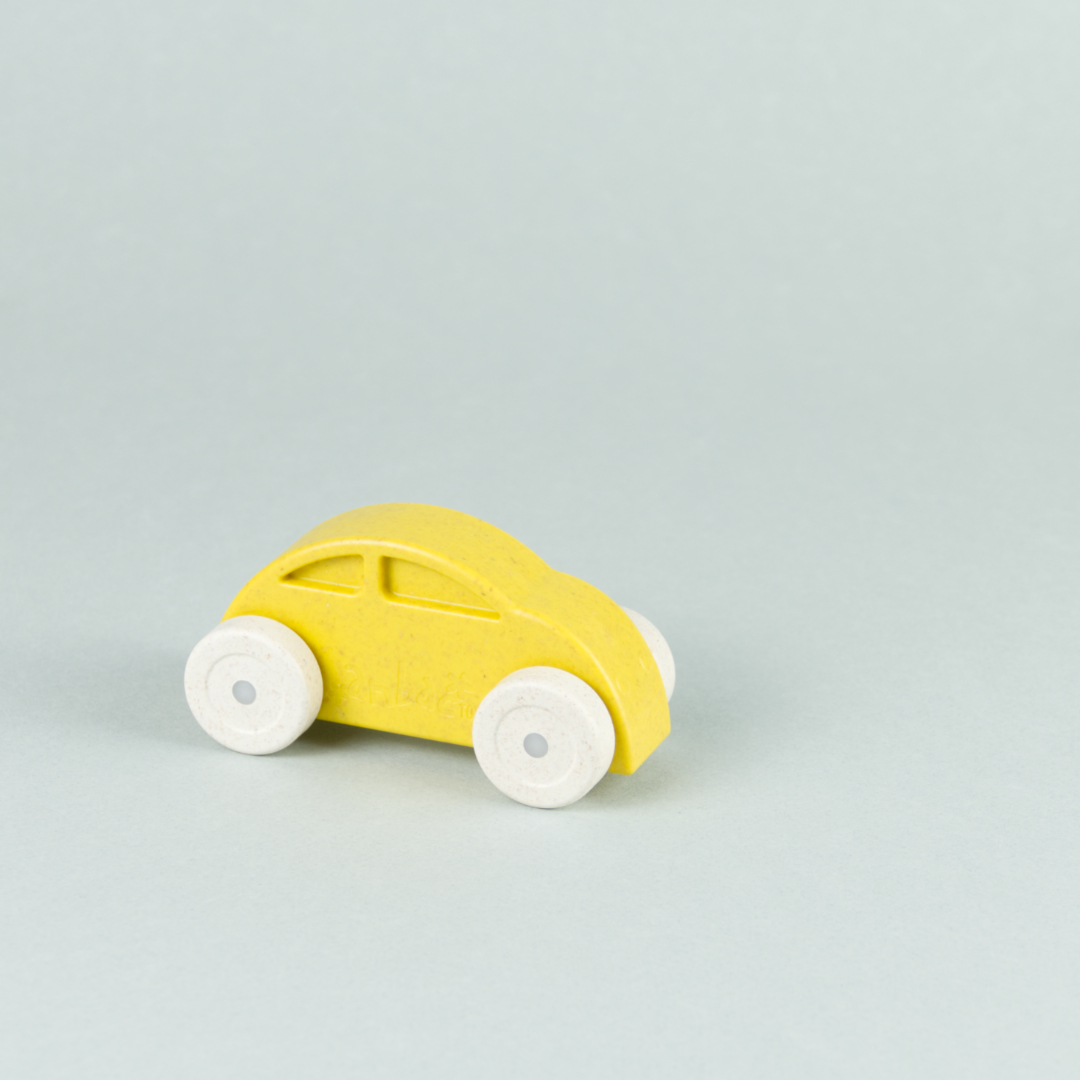 Gelbes Spielzeugauto aus einem Kunststoff und Holz Gemisch.