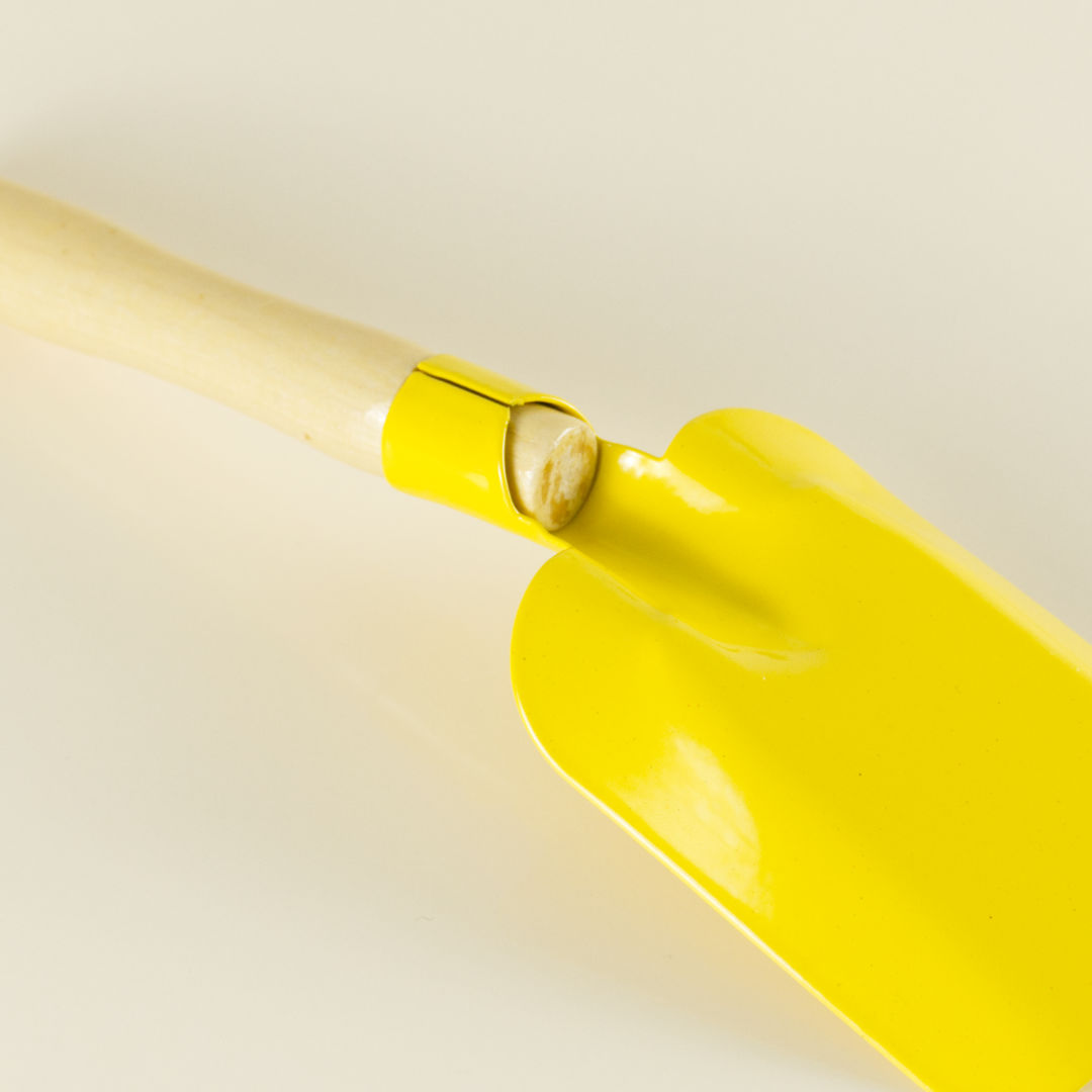 Kleine Spielschaufel in Gelb, aus Metall mit Holzgriff.