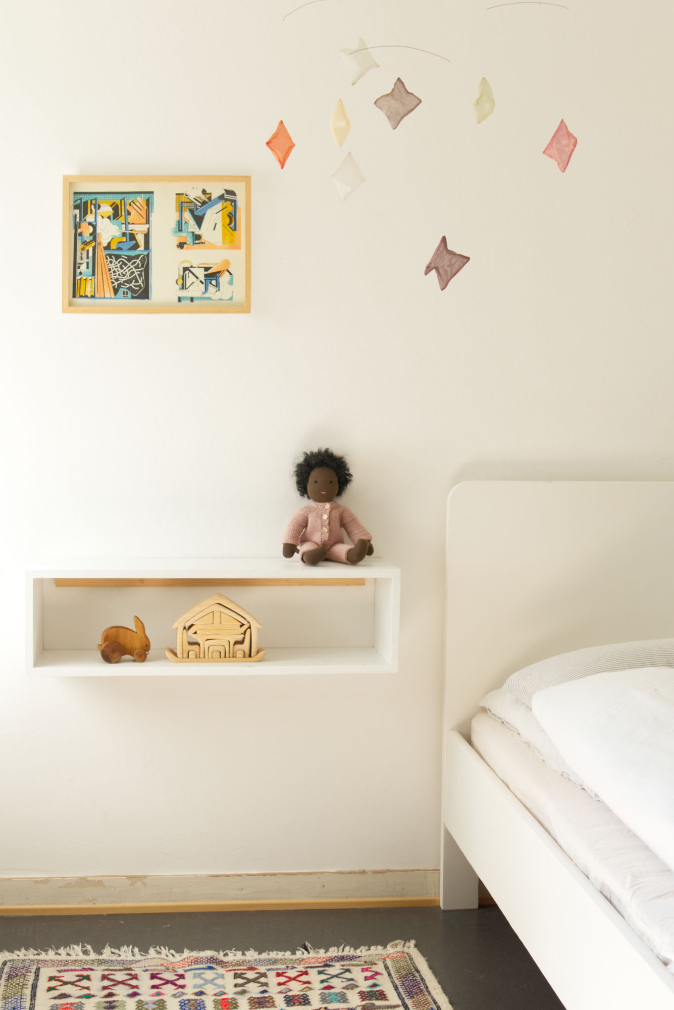 Einblick in ein Kinderzimmer. Zu sehen sind verschiedene Spielsachen, wie eine sitzende Puppe, ein Holzhase und ein Holz-Bauset.