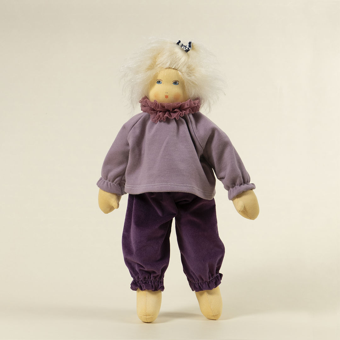 Nanchen Puppe mit heller Haut und hellblonde Haaren stehend. Sie trägt einen Pullover in Flieder mit Kragen und eine lila Hose.