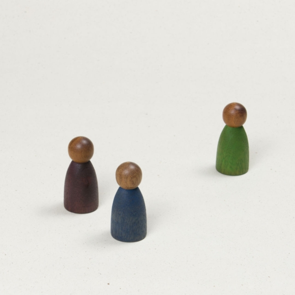 Drei gleichförmige Holzfiguren mit dunklerer Hautfarbe und Körpern in blau, lila und grün.