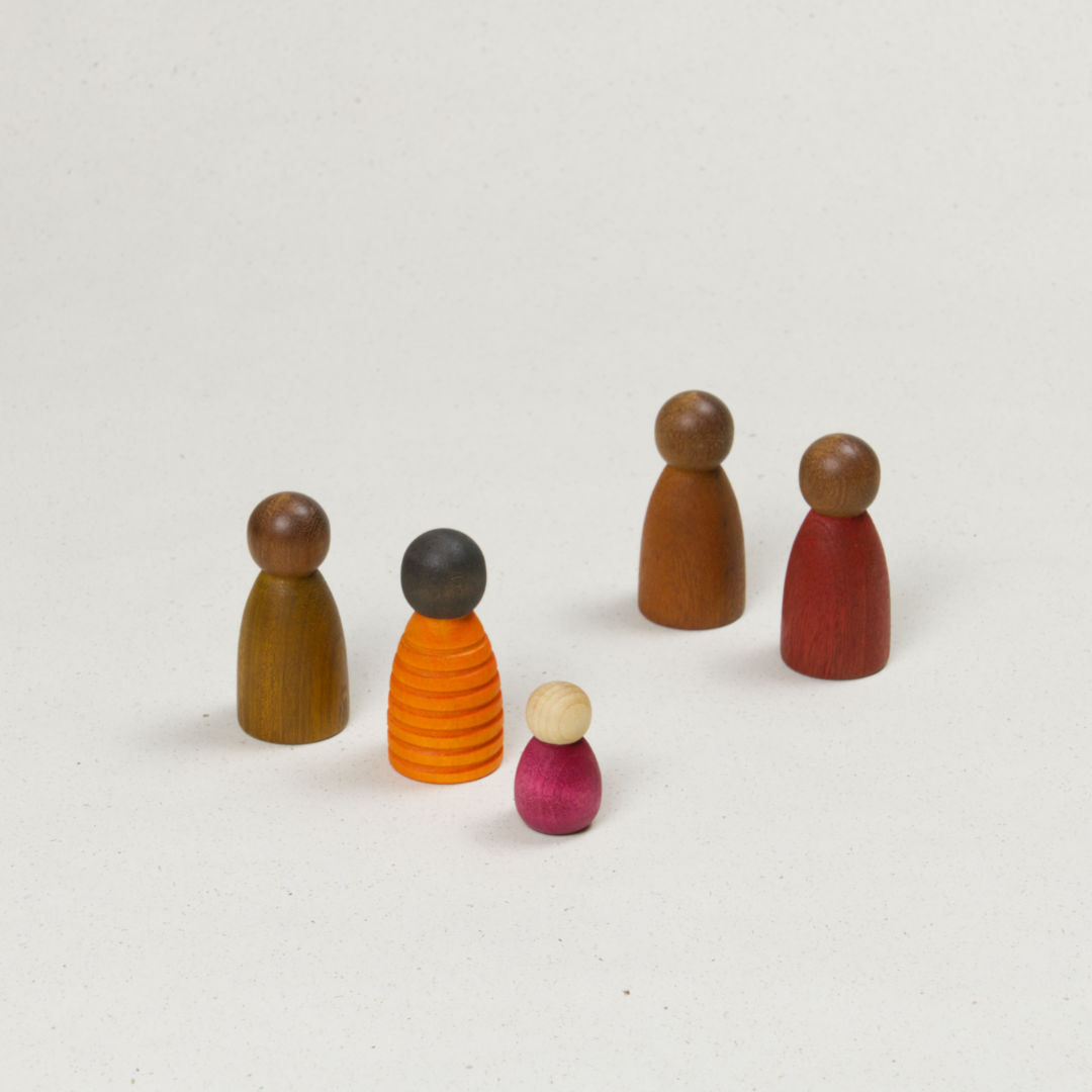 Fünf unterschiedlich geformte Holzfiguren mit verschiedenen Hautfarben in Gelb, Rot und Orange.
