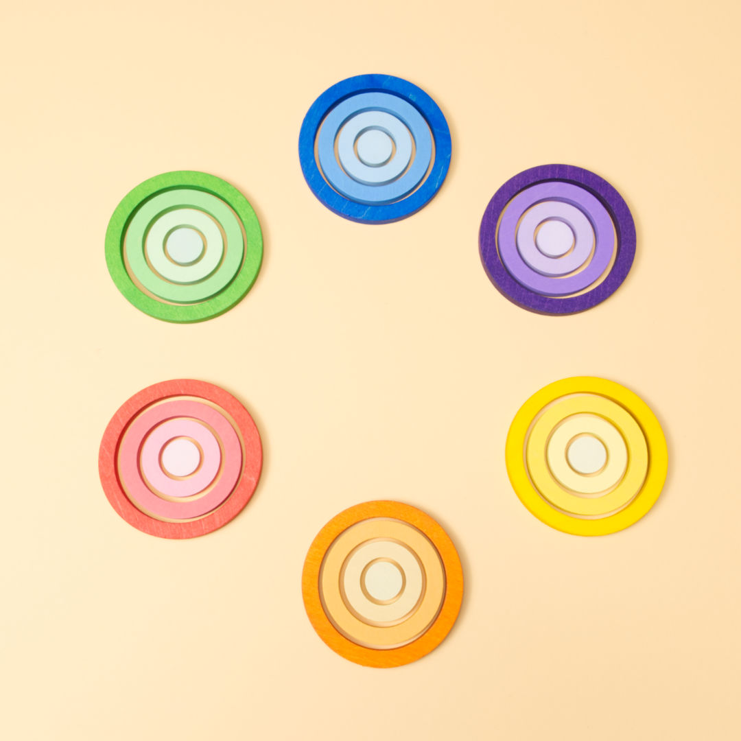 Sechs lila, blaue, gelbe, orangene, rote und grüne Ringe, in welchen je drei weitere drin liegen mit abgeschwächten Farbverlauf. Im Kreis angeordnet.