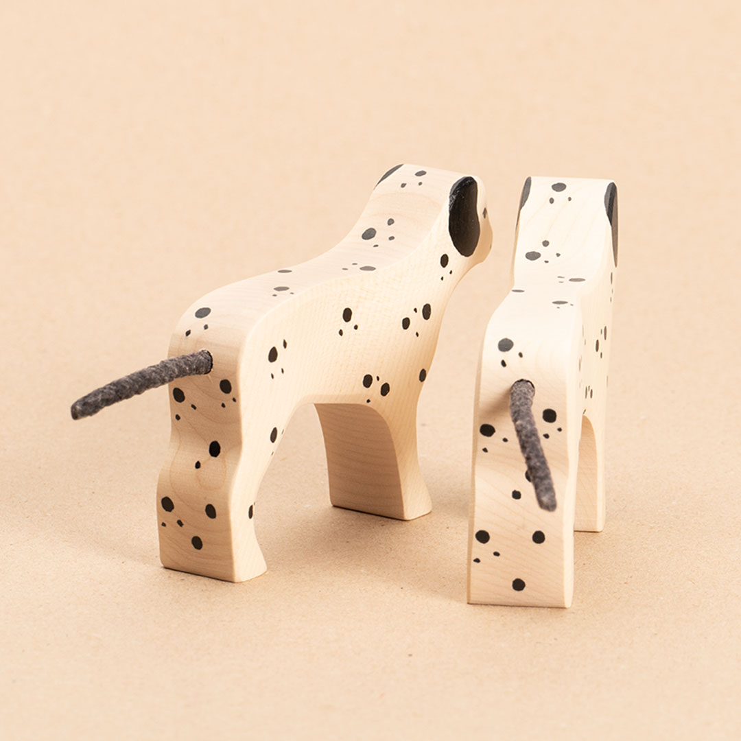 Zwei Dalmatiner aus Holz. Weiß bemalt mit schwarzen Punkten und Ohren. Beide schauen nach Hinten rechts