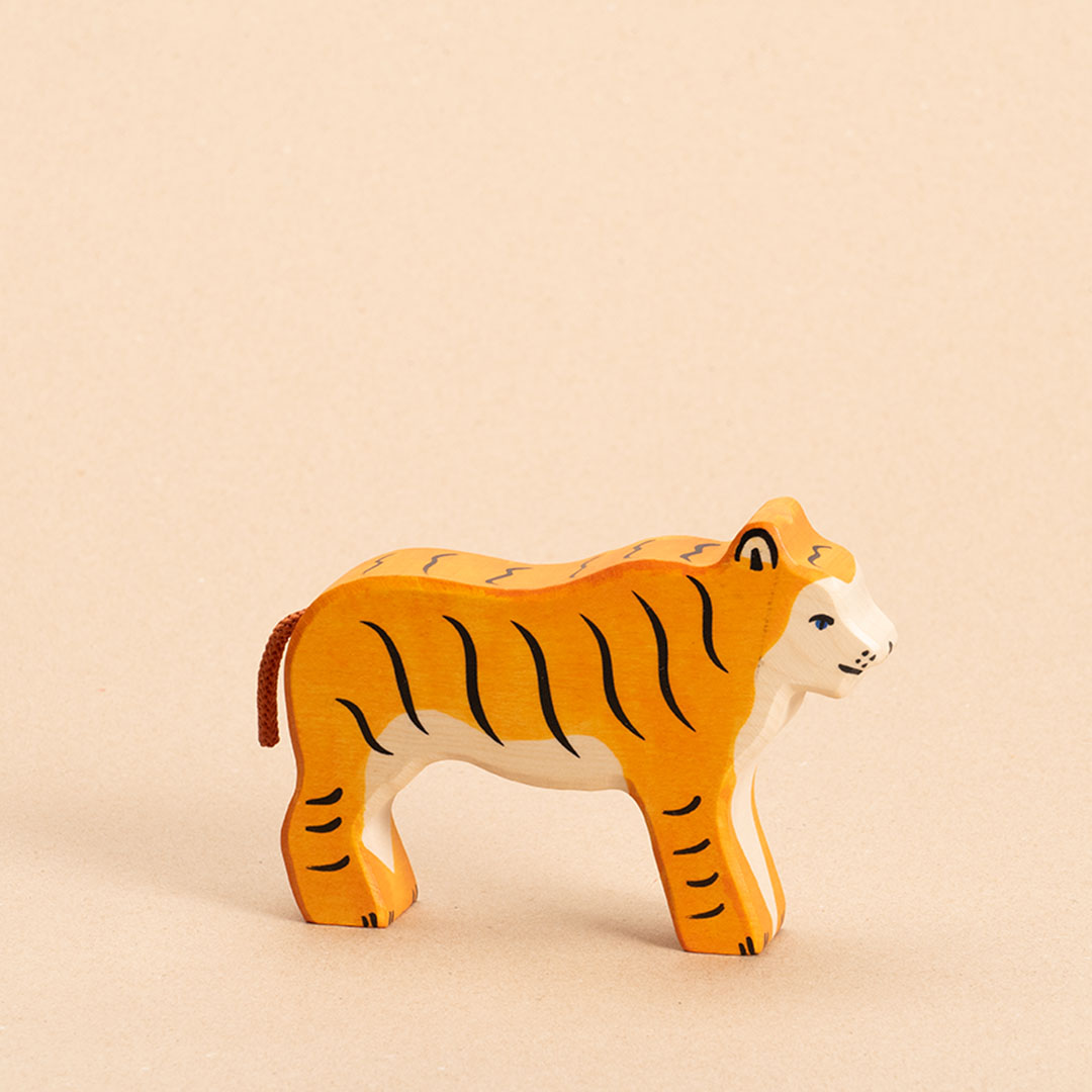 Ein nach rechts schauender Tiger im Profil aus Ahorn- und Buchenholz gefertigt, hat orangenes Fell mit schwarzen, senkrechten Streifen. Das Gesicht und Bauchfell sind weiß. Sein orangener Schwanz aus Kordel ist nach unten hin geneigt.