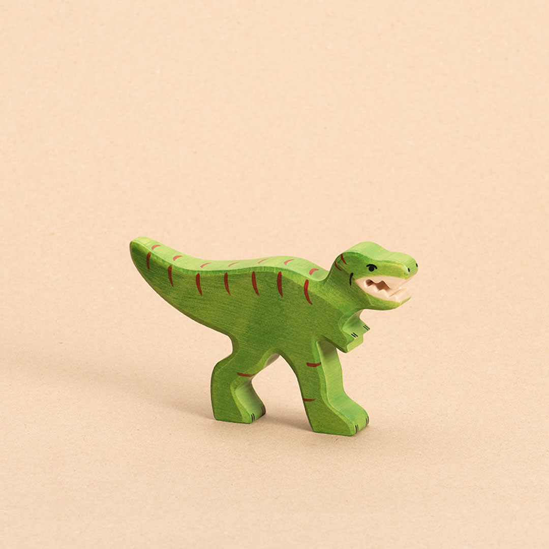 Ein intensiv grüner Tyrannosaurus Rex aus Holz mit geöffnetem Mund und spitzen weißen Zähnen, hat rote Farbdetails, einen waagerecht nach hinten geformten Schwanz und sehr kurze nach vorne stehende Arme. Er schaut im Profil nach rechts.