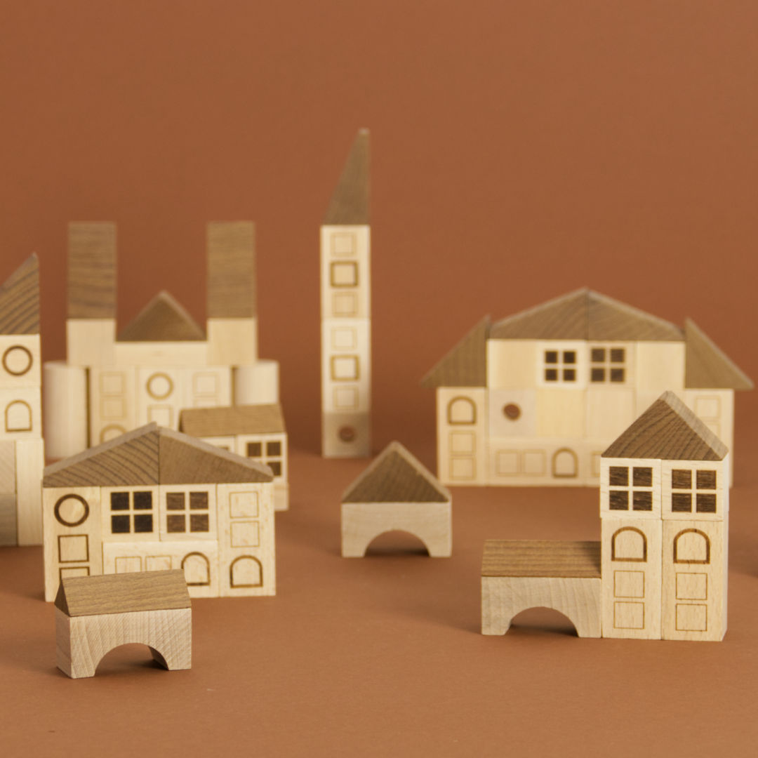 Ein Arrangement einer Stadt von Vorne aus Bausteinen, gefertigt aus Maserholz von Goki. Die Häuser im Hintergrund sind unscharf.