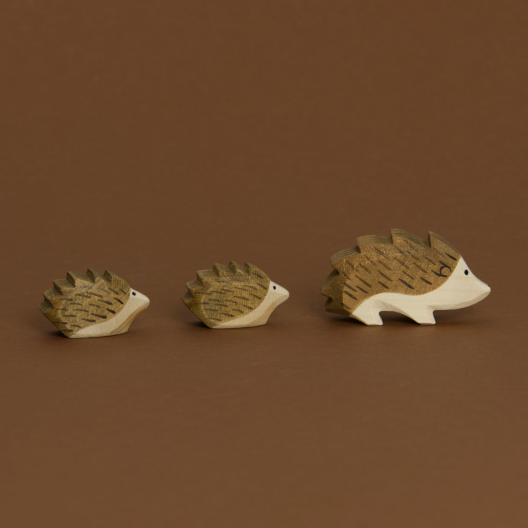 Eine Komposition von drei Igeln, aus Igel, Igel klein und Igel klein, im Profil nach rechts schauend, sind von Ostheimer aus Naturholz gefertigt. Alle haben braune Stacheln und helles Bauchfell. Beide kleinen Igel folgen dem Igel.