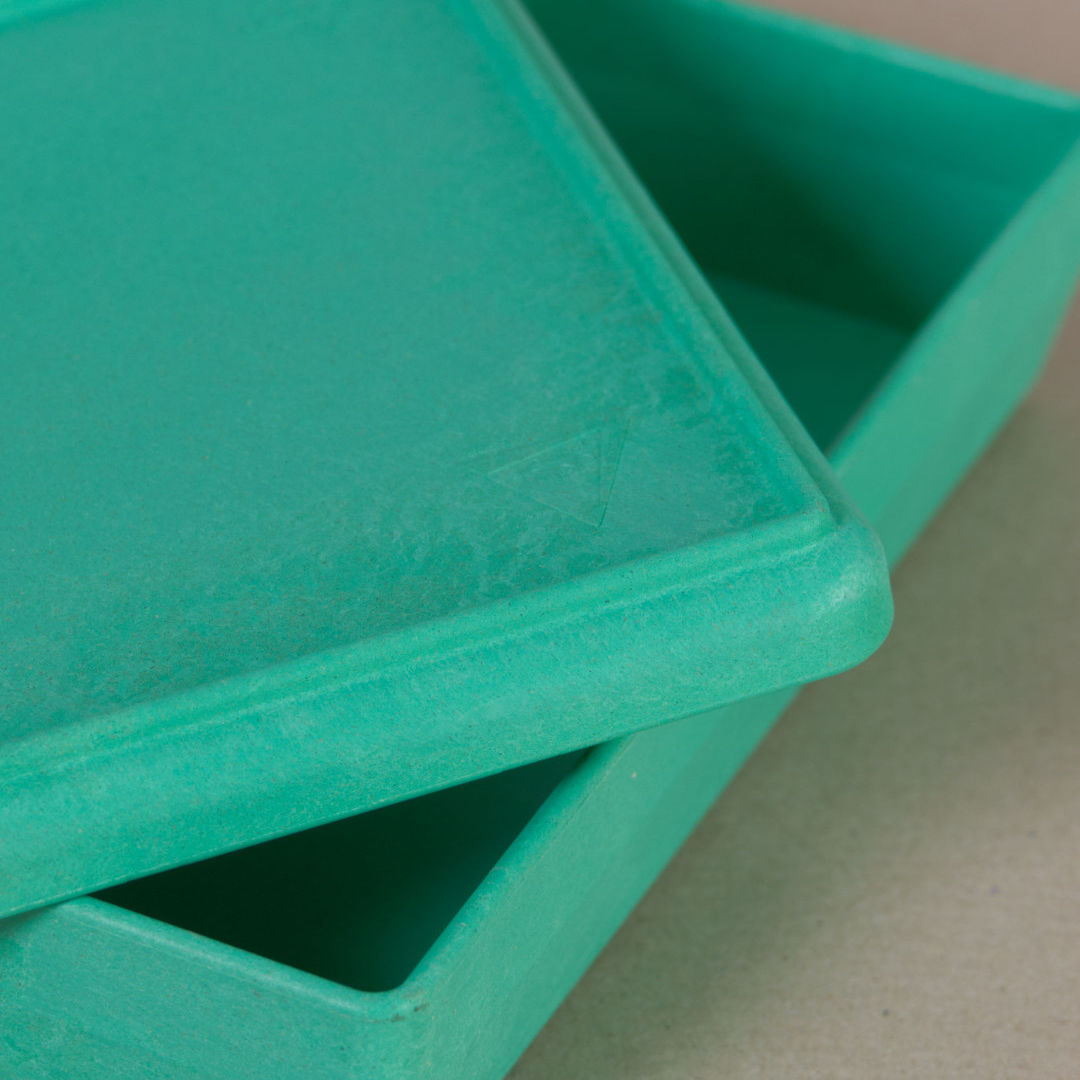 Nahaufnahme von der aus recyclebarem Material bestehende grüne Box von Wissner, mit halboffenem Deckel daliegend.
