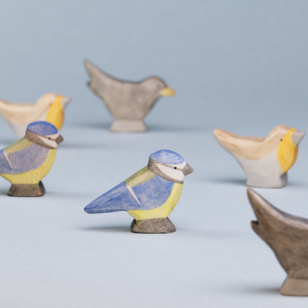 Komposition aus Holzvögeln der Firma Holzviecherl. Im Mittelpunkt Blaumeise, umspielt von Rotkelchen und Amsel