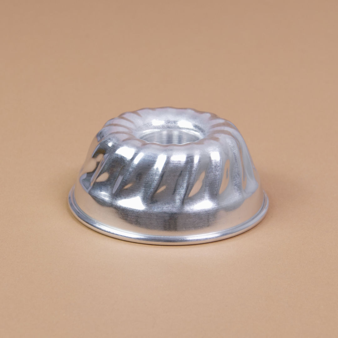 Eine Gugelhupfform aus Aluminium liegt mit der Öffnung nach unten da und hat einen Durchmesser von 10 cm.