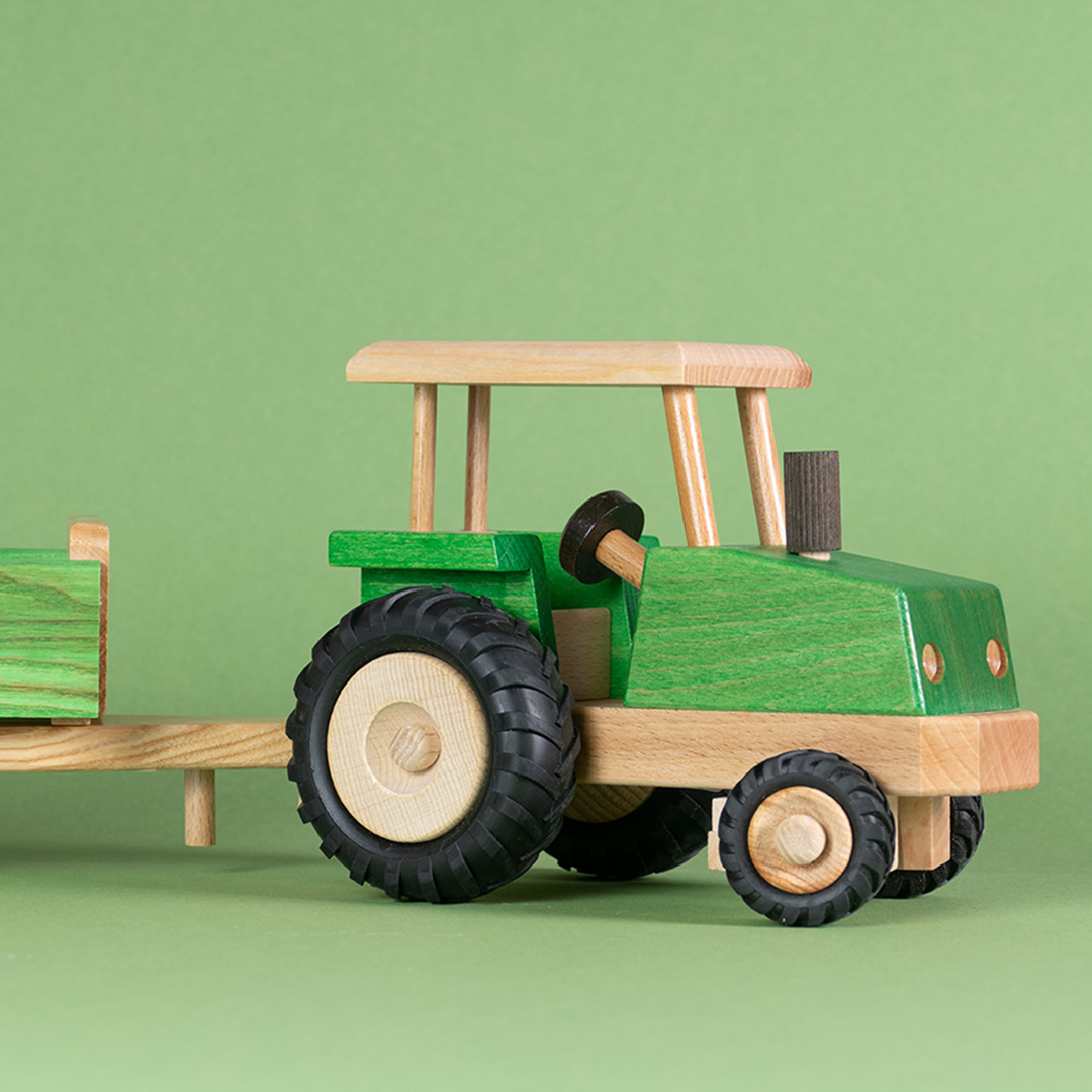 Seitenansicht eines grünen, lenkbaren Traktors von Beck mit Anhänger.