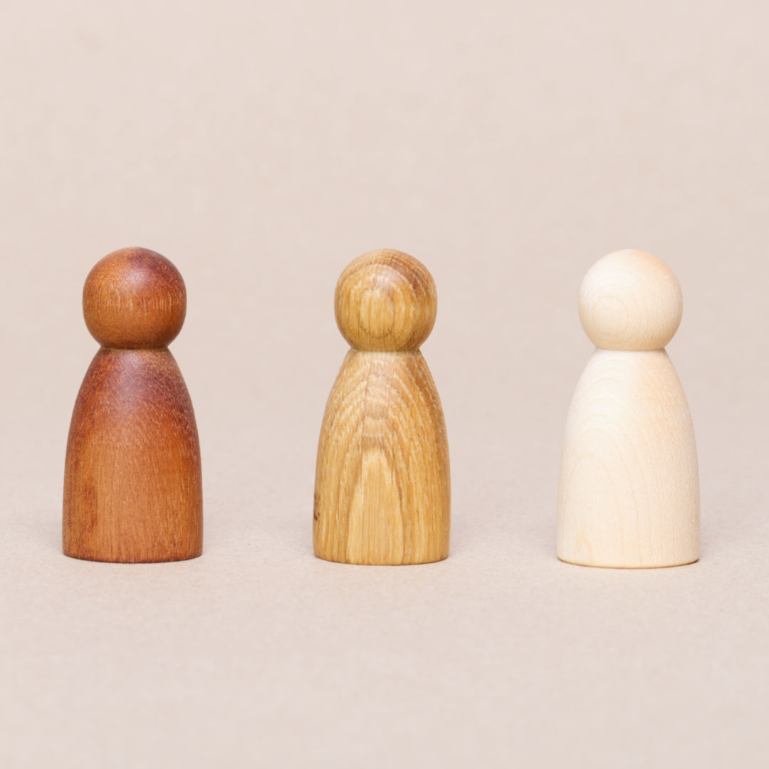 Drei Holzfiguren in drei unterschiedlichen Holzarten von Grapat. Rechts in weiß Natur, in der Mitte in hellbraun Natur und links dunkelbraun Natur.