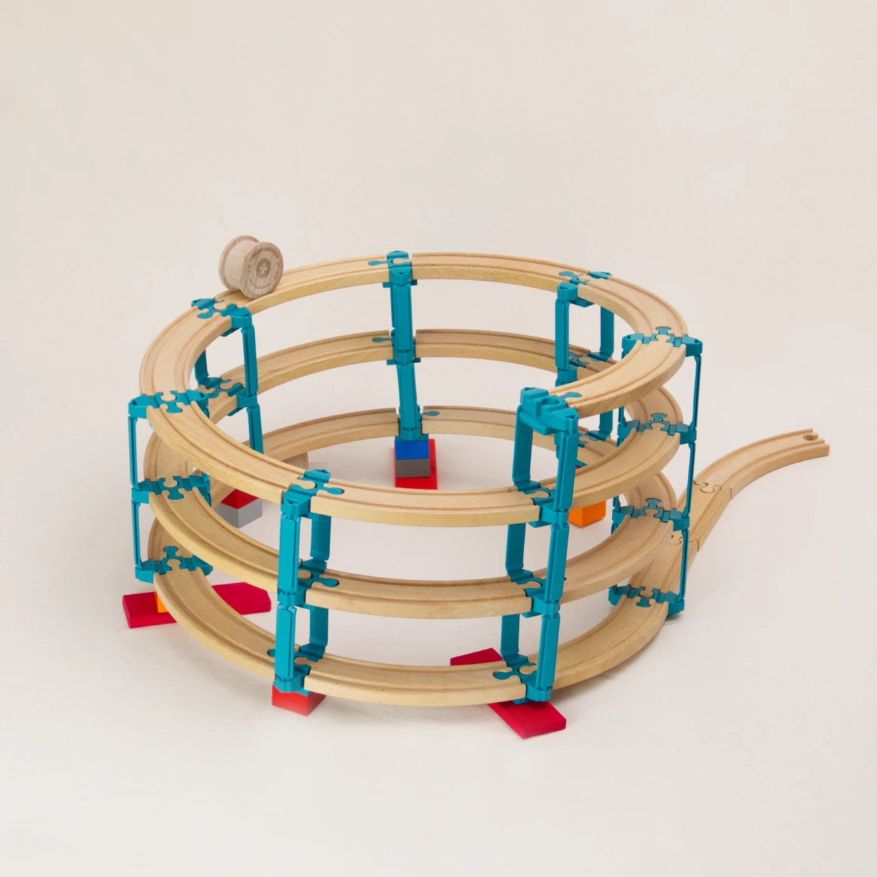 Das Adapter Set Helix 3 von Yamba ermöglicht es mit seinen Bauelementen die Verbindung von Klemmbausteinen (DUPLO®, BioBUDDi®, Hubelino® usw.) und Schienen (BRIO®, IKEA®, Eichhorn®, Hape® usw.) in ein Säulensystem auf zu bauen, was über mehrere Ebenen gehen kann. Zu sehen ist das Set Helix 3, das mittlere Paket mit insgesamt 57 Elementen, mit diesen kann man bis zu vier Stockwerke im Kreis nach oben bauen. Es gibt vier unterschiedliche Bauelemente: Verbindungsstück LinkUp, Verbindungsstück Cross, Säule Lift, Verbindungsknochen Bar. Zusätzlich enthält jedes Set eine Holzwalze genannt Rolli der auf den hölzernen Schienen selbstständig nach unten rollt.