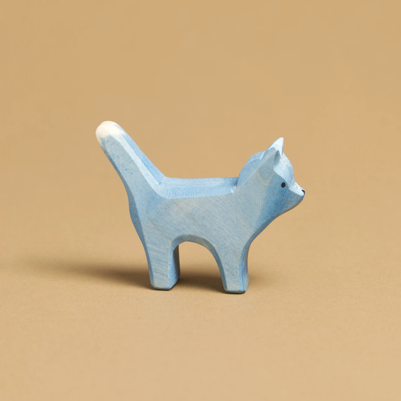 Eine blaue Katze, im Profil nach rechts schauend, ist von Ostheimer aus Naturholz gefertigt. Ihr Schwanz und ihre Ohren sind nach oben hin gerichtet.