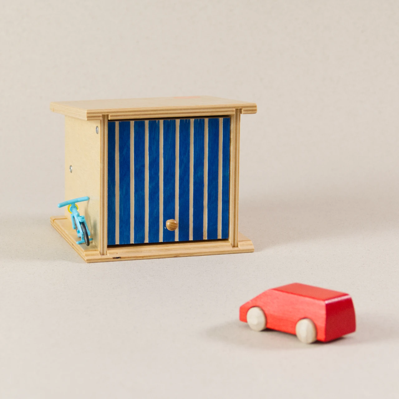Doppelgarage von Beck zum Spielen, aus Holz. Das Garagentor ist blau und lässt sich aufklappen. Ein rotes Auto aus Holz ist dabei.