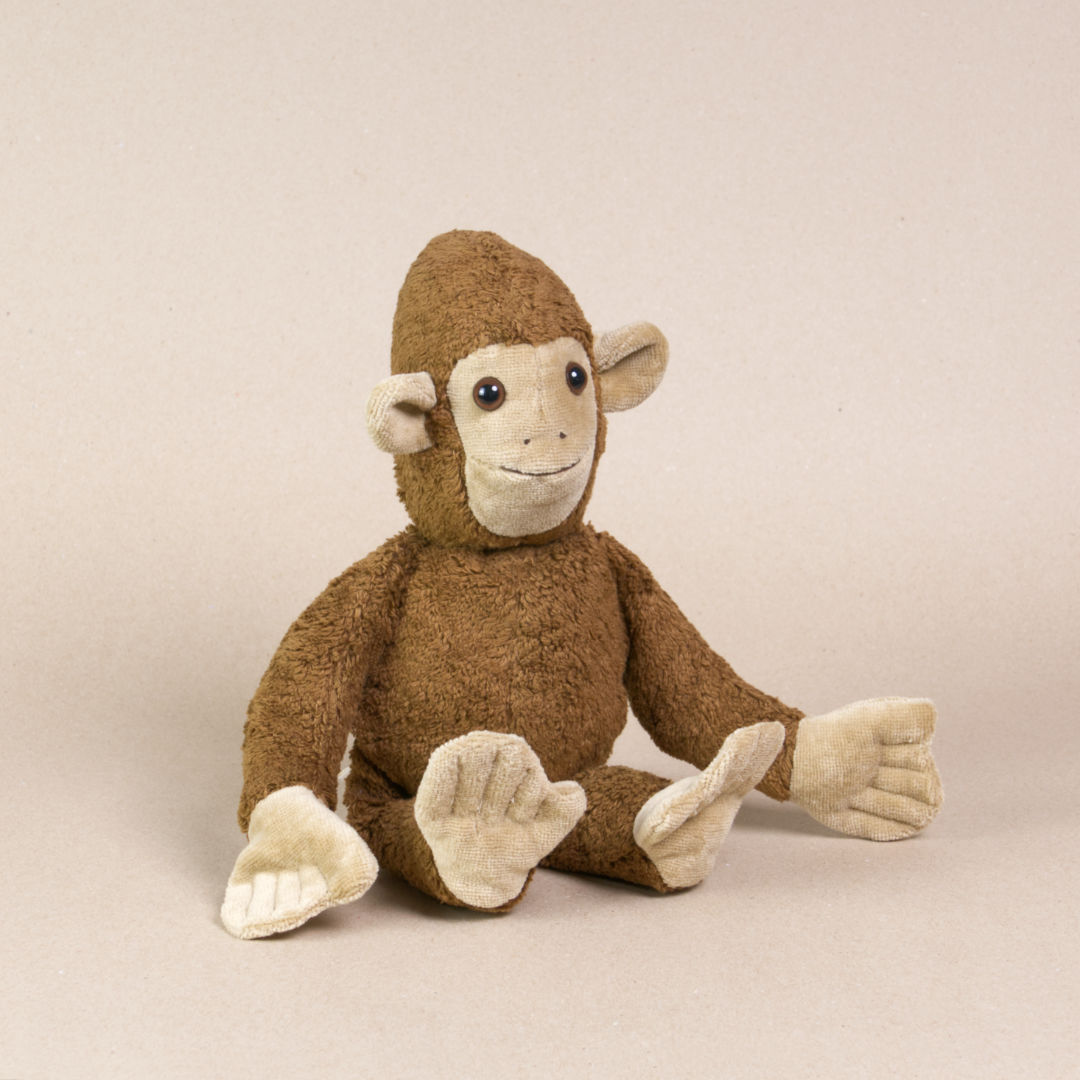 Vorderansicht des Kuscheltieres Affe namens Toto von Kallisto. Es hat braunes Plüschfell und braune Knopfaugen. Es sitzt aufrecht im Bild.