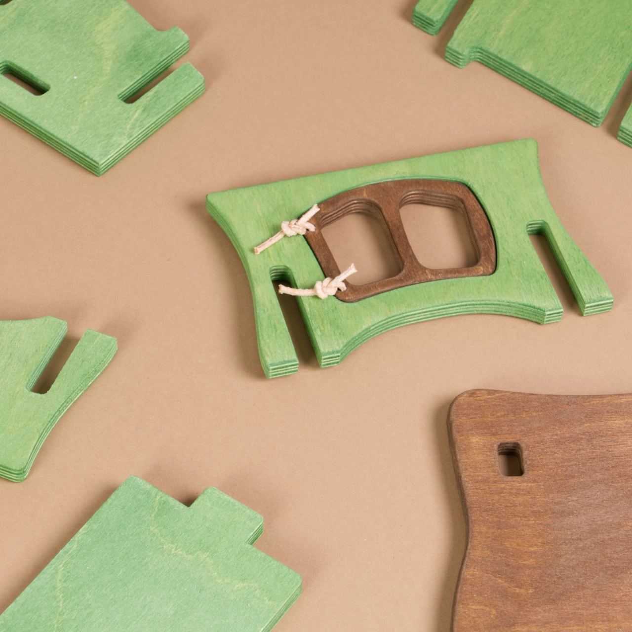 Komposition eines hellgrünen Hasenstalls von Ostheimer mit brauner, beweglicher Tür, die mit einer Kordel befestigt ist und einem braunen Dach. Alles lässt sich in Einzelteile zerlegen und auch wieder zusammenstecken.