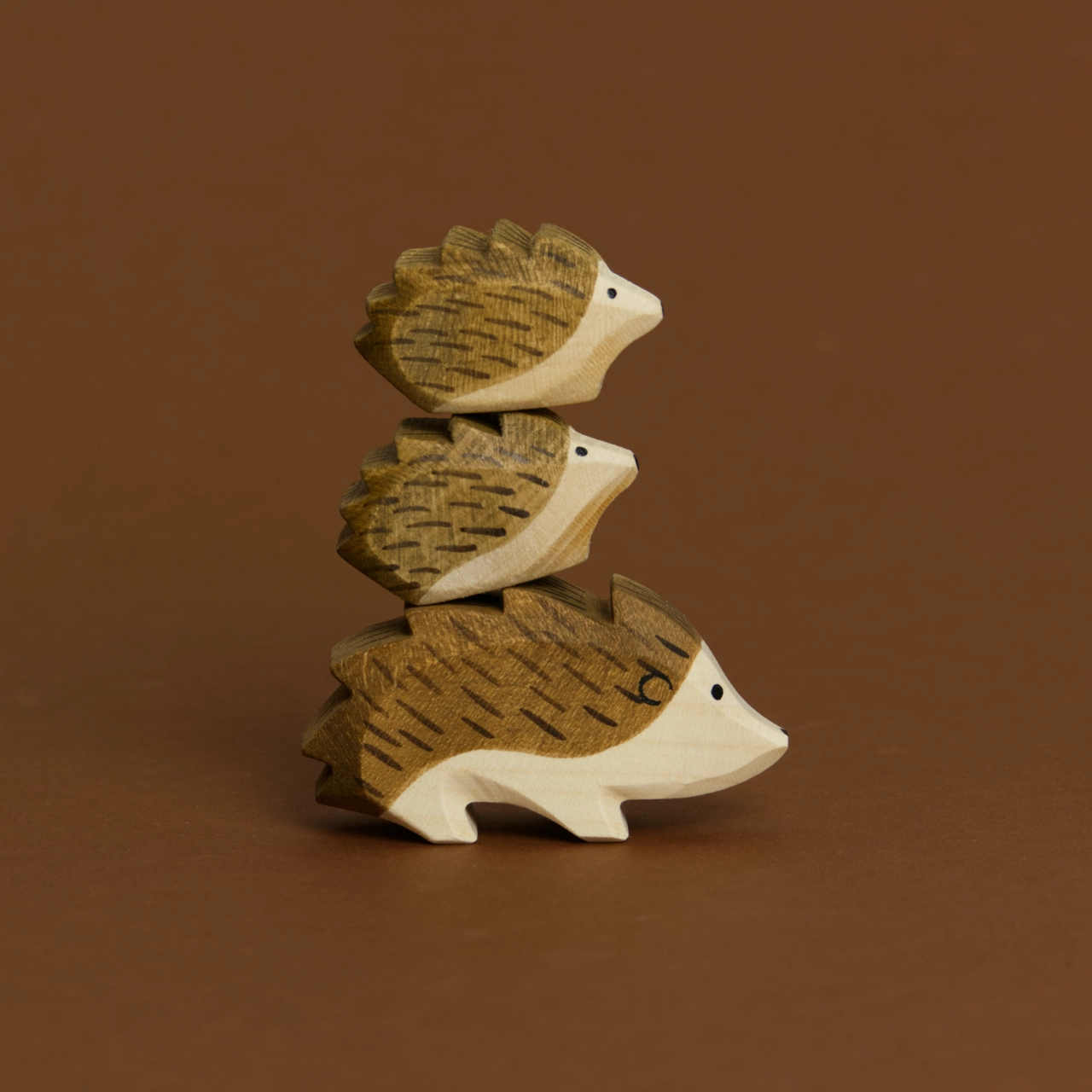 Eine Komposition von drei Igeln, aus Igel, Igel klein und Igel klein aufeinandergetürmt, im Profil nach rechts schauend, sind von Ostheimer aus Naturholz gefertigt. Alle haben braune Stacheln und helles Bauchfell.