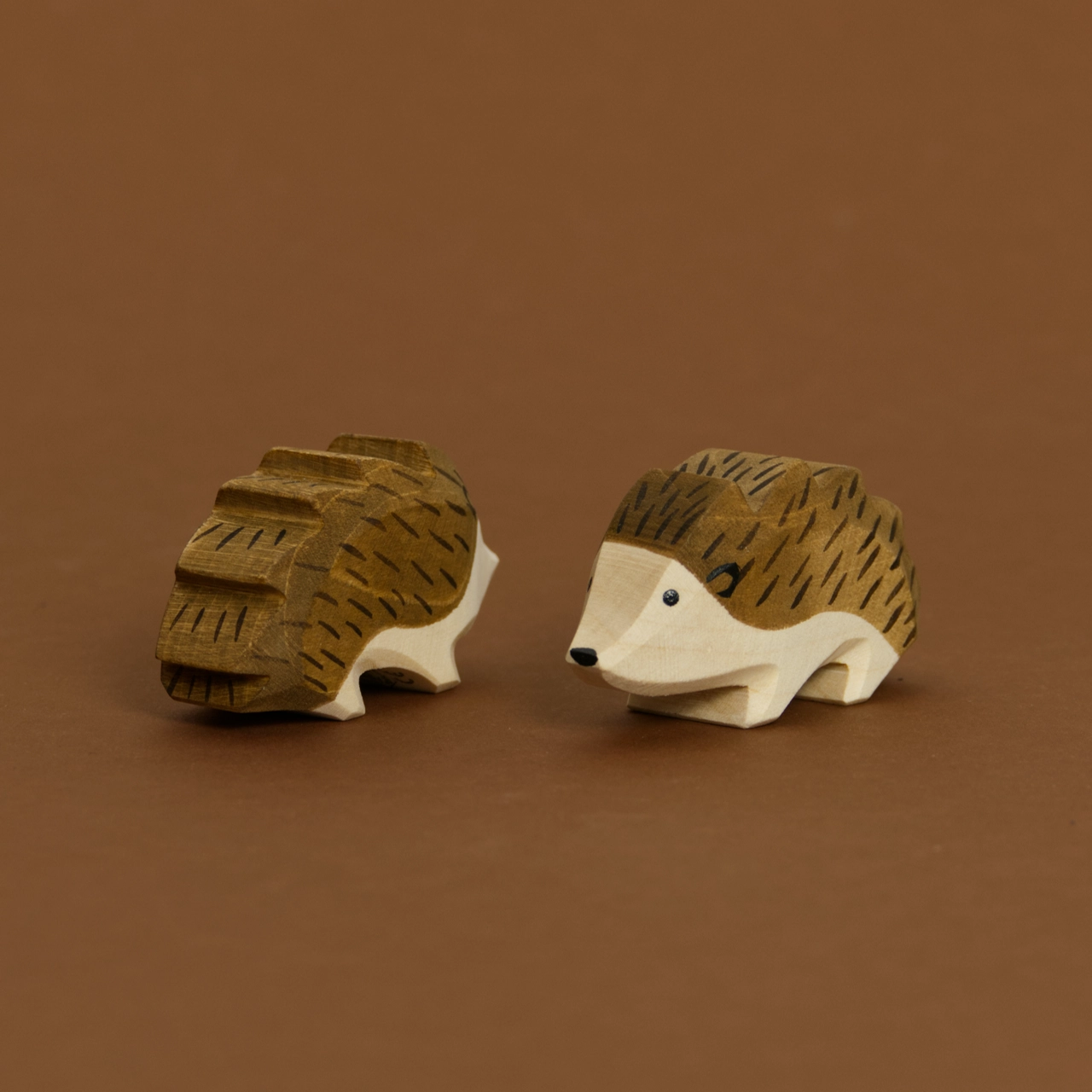 Zwei Igel von Ostheimer aus Naturholz gefertigt, beide haben dunkelbraune Stacheln und naturfarbenes Bauchfell. Der Rechte schaut nach vorne links und der Linke nach hinten rechts.