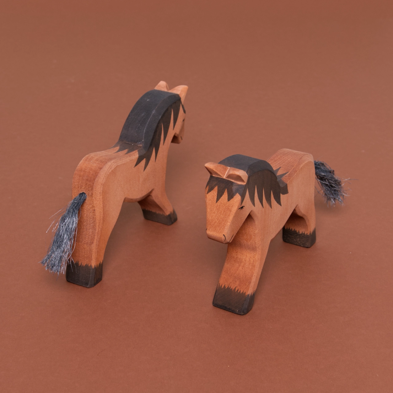 Zwei nach rechts schauende Kaltblutpferde mit braunem Fell, dunkelbraunen Hufen und Mähne, haben einen Schweif aus Naturhaar und sind von Ostheimer gefertigt.