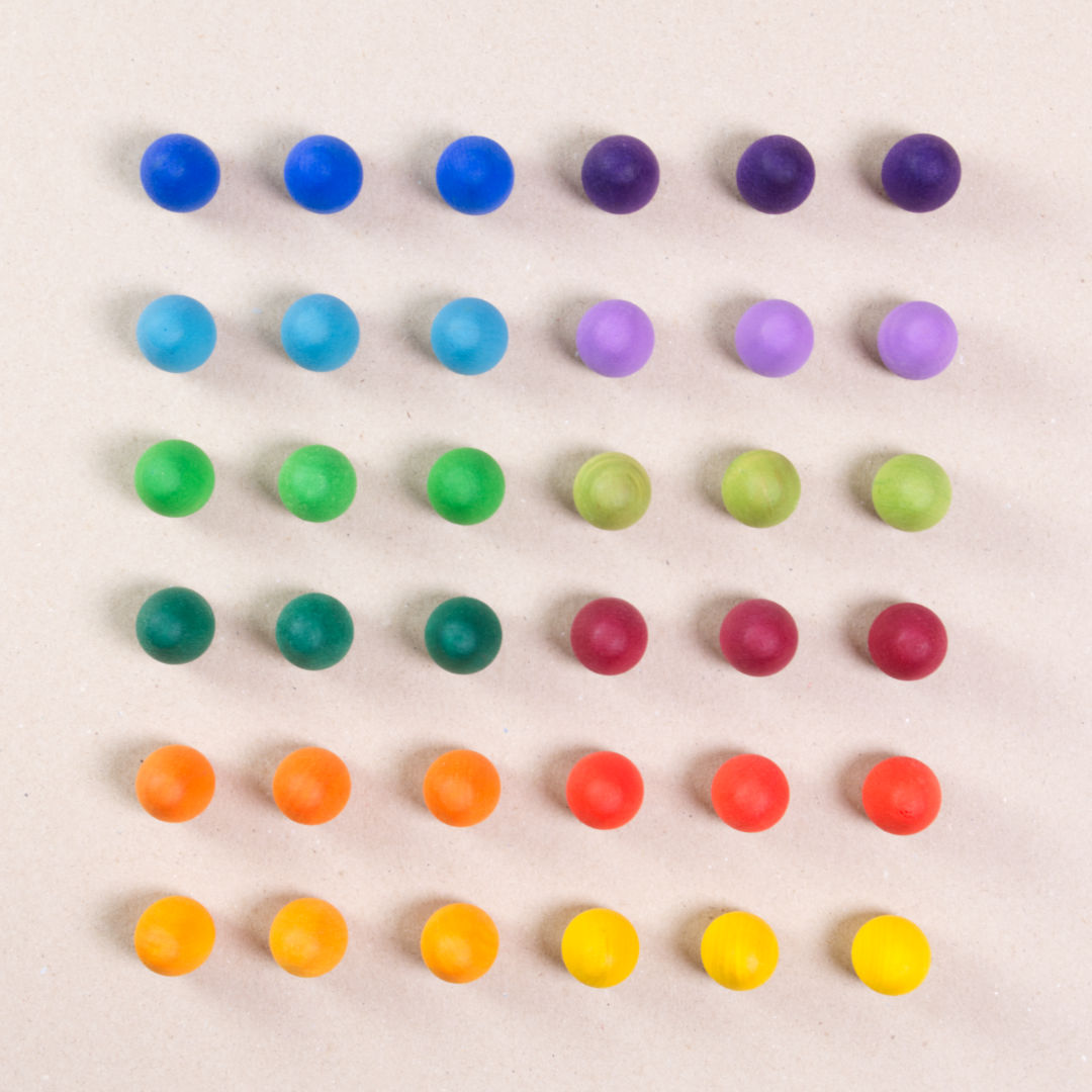 36 Regenbogen Eier aus Holz von Grapat in 12 unterschiedlichen Farben. Dunkelblau, dunkellila, hellblau, pastelllila, grasgrün, hellgrün, dunkelgrün, dunkelrot, orange, rot, sonnengelb und senfgelb. Gemeinsam als Quadratischer Block aufgebaut. Ansicht von Oben.