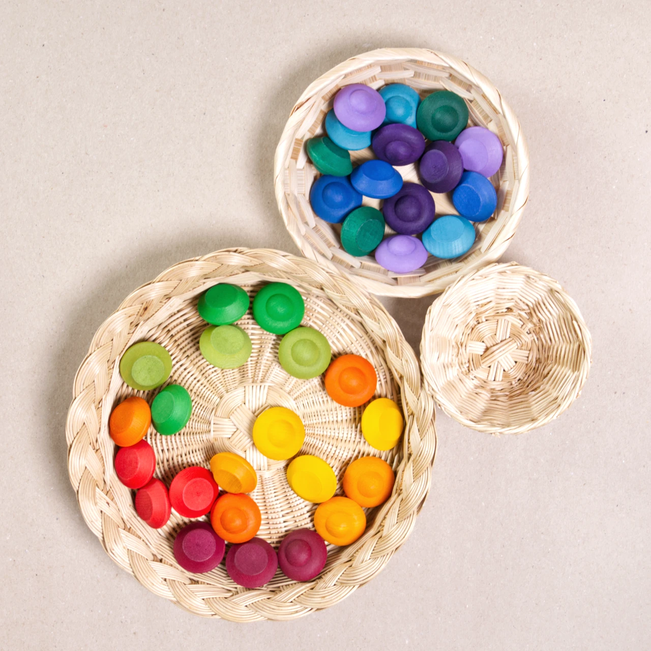 Komposition aus den Figuren aus dem Set Mandala Rainbow flowers von Grapat. Alle Holzfiguren sind bunt. Alle sind in vier Körbchen aufgeteilt.