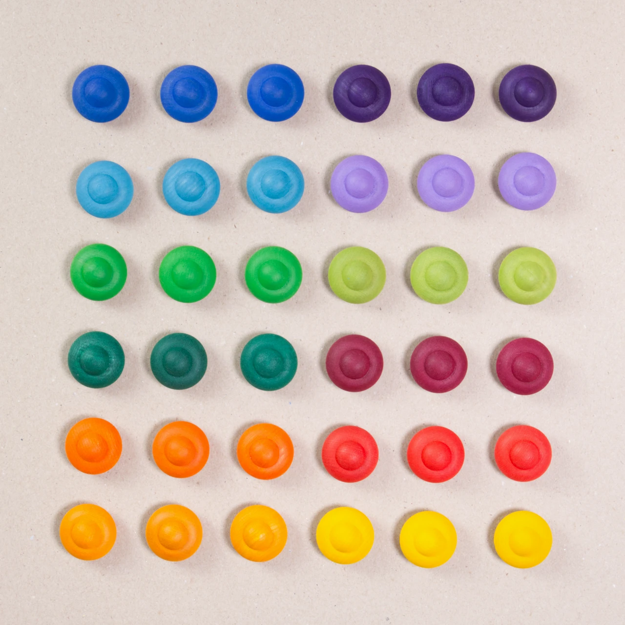 36 Regenbogen Blumen aus Holz von Grapat in 12 unterschiedlichen Farben. Dunkelblau, dunkellila, hellblau, pastelllila, grasgrün, hellgrün, dunkelgrün, dunkelrot, orange, rot, sonnengelb und senfgelb. Gemeinsam als Quadratischer Block aufgebaut. Ansicht von Oben.