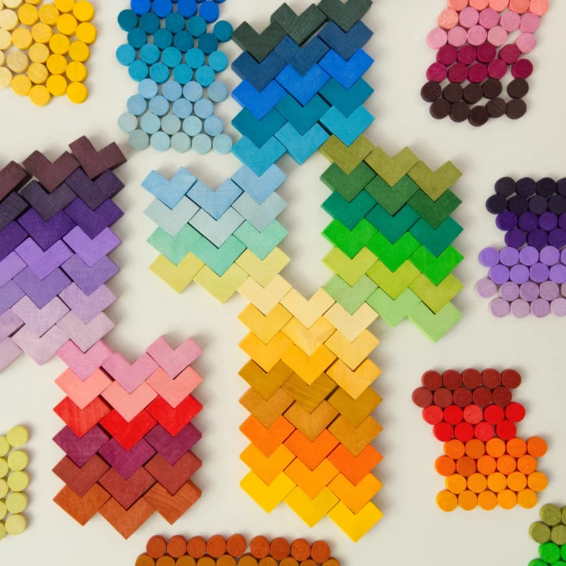 Grapat Mis Match and Bloom, Mosaik Elemente, 400 Teile, 36 Farbnuancen – bunte Zylinder- und Eckelemente in Farbverläufen sortiert und mosaikartig auf einer hellen Fläche angeordnet, Regenbogenfarben von Gelb über Grün, Blau und Violett bis zu Rot, symbolisieren kreative Legemöglichkeiten