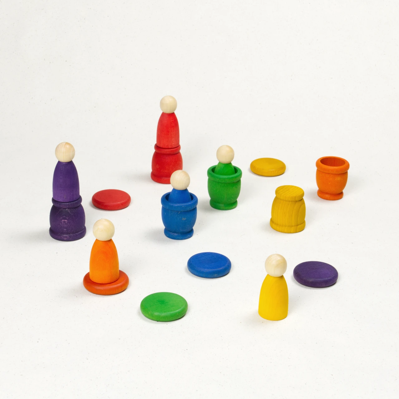 Sechs bunte Nins in und auf farblich passenden Töpfchen mit münzförmigen Deckeln.