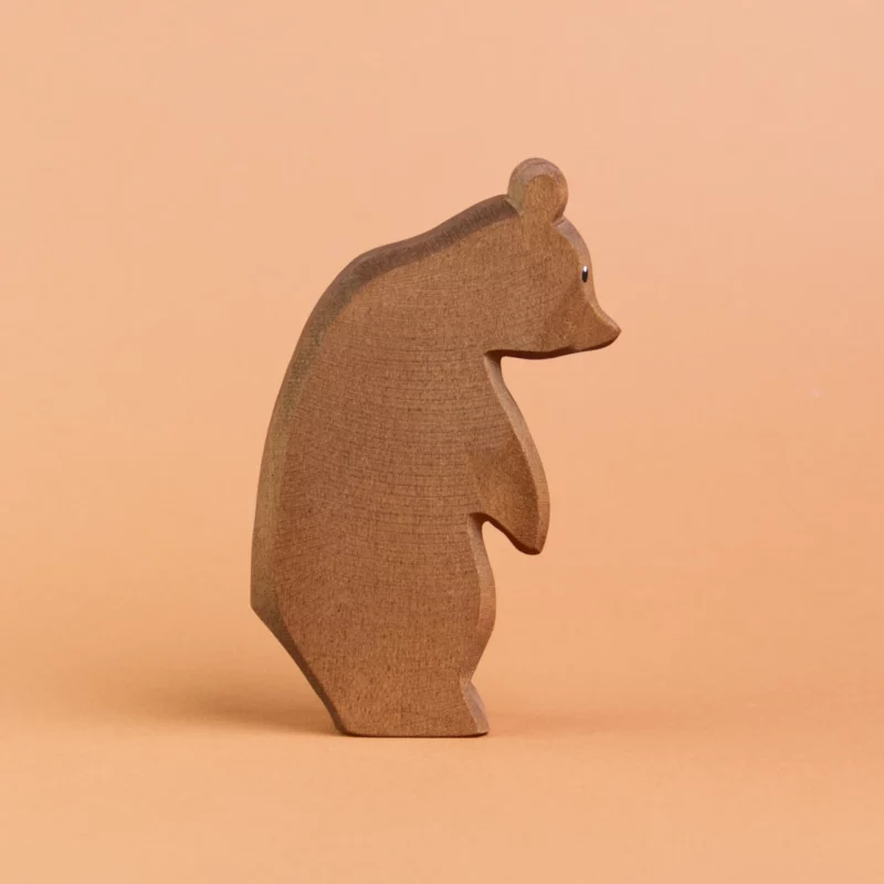 Ein Bär aus Holz ist stehend in der Seitenansicht zu sehen und schaut nach rechts. Er hat dunkelbraunes Fell und große, runde Ohren. Er ist von der Marke Ostheimer.