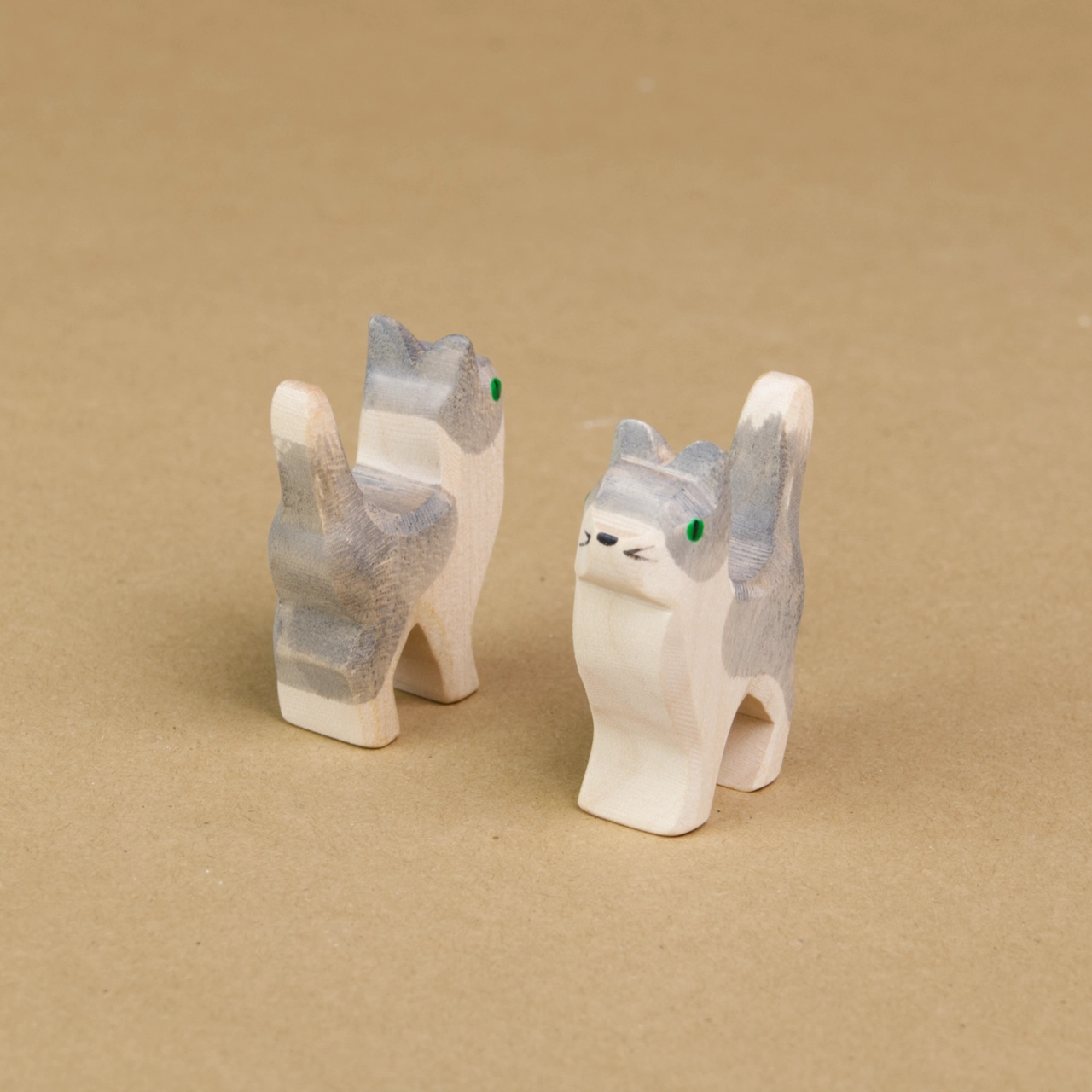 Zwei kleine Katzen mit weiß-grauem Fell stehen parallel, schräg nebeneinander und halten ihren Kopf sowie den Schwanz nach oben. Die linke Katze schaut nach hinten rechts und die rechte Katze schaut nach vorne links und ist mit dem Gesicht zu sehen.