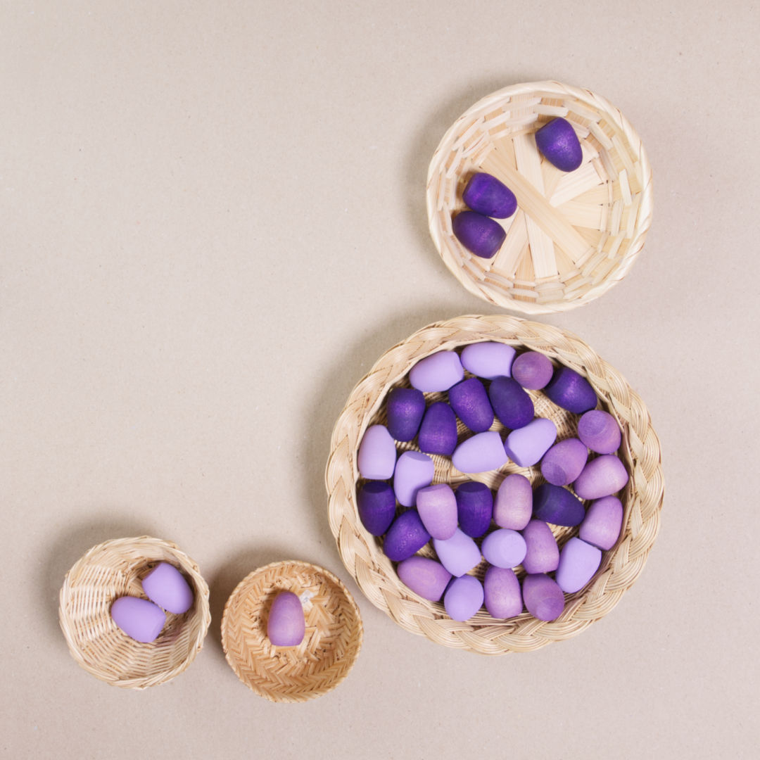 Komposition aus den Figuren aus dem Set Mandala purple eggs von Grapat. Alle Holzfiguren sind lila. Alle sind in vier Körbchen aufgeteilt.