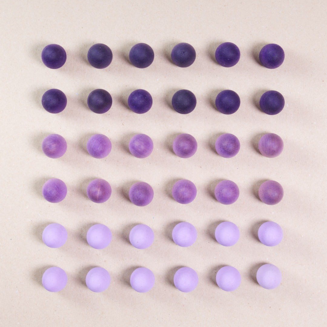 36 Ei Holzfiguren von Grapat in drei unterschiedlichen Farben. Helllila, violett und dunkellila. Gemeinsam als Quadratischer Block aufgebaut. Ansicht von Oben.