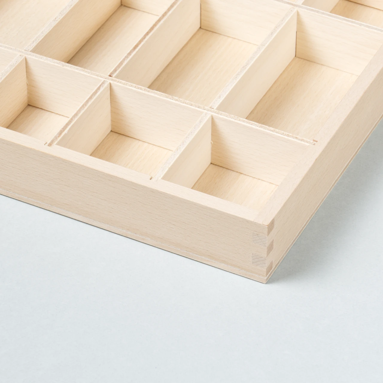 Die Verarbeitung einer Ecke der Sortierbox Tinker Tray aus Naturholz mit verschieden großen Fächern zum Sammeln, Ordnen und Aufbewahren von Spielzeug, hier noch ungefülllt zu sehen.