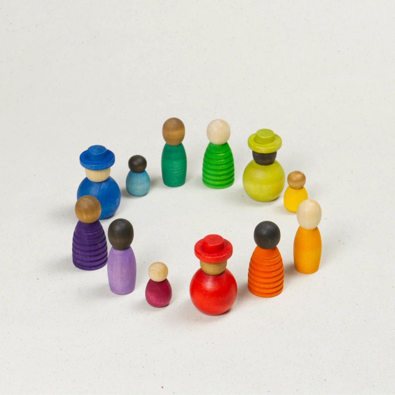 Sammlung verschiedener bunter Holzfiguren mit unterschiedlichen Hautfarben, Formen und Größen in einem Kreis angeordnet.