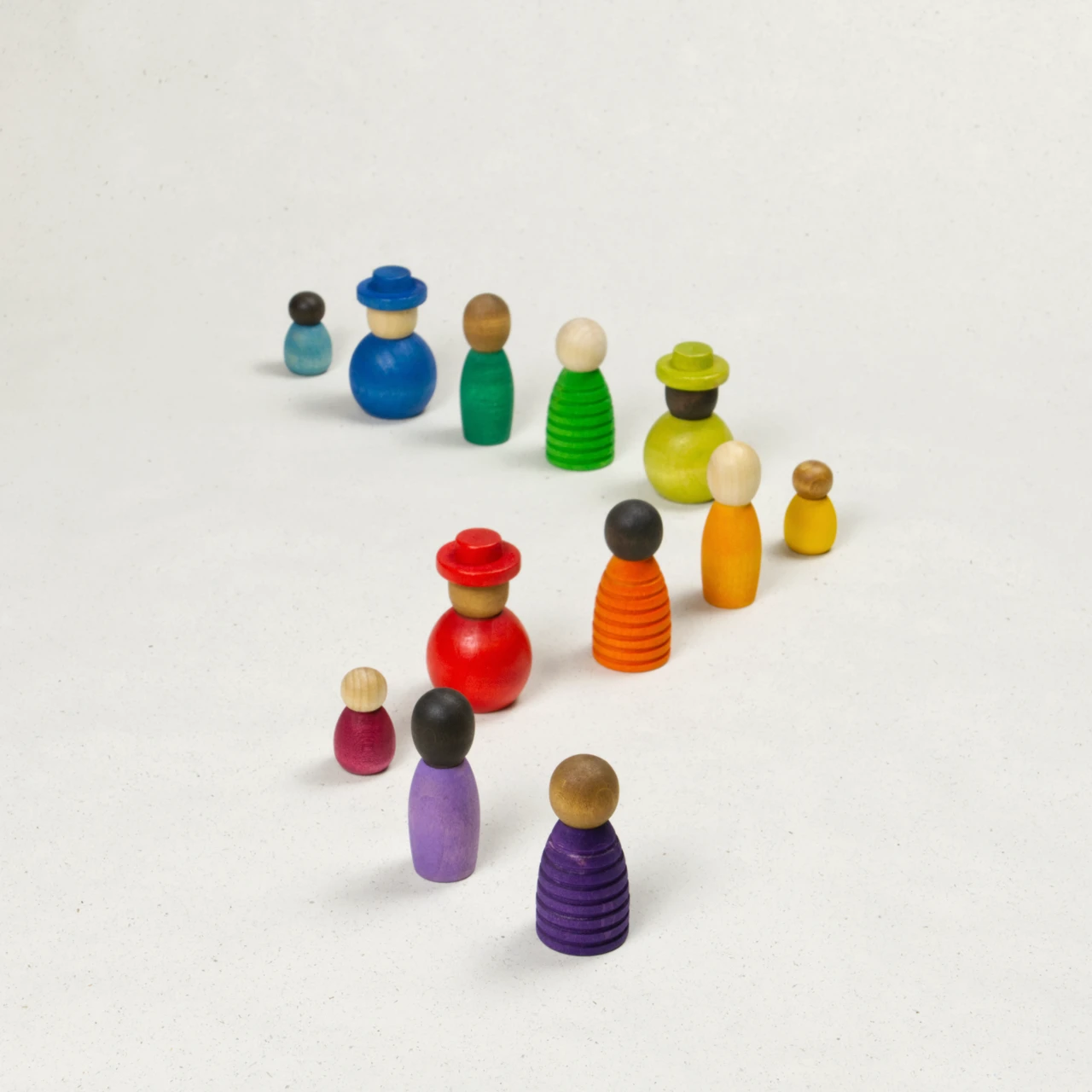 Sammlung verschiedener bunter Holzfiguren mit unterschiedlichen Hautfarben, Formen und Größen im Zickzack angeordnet.