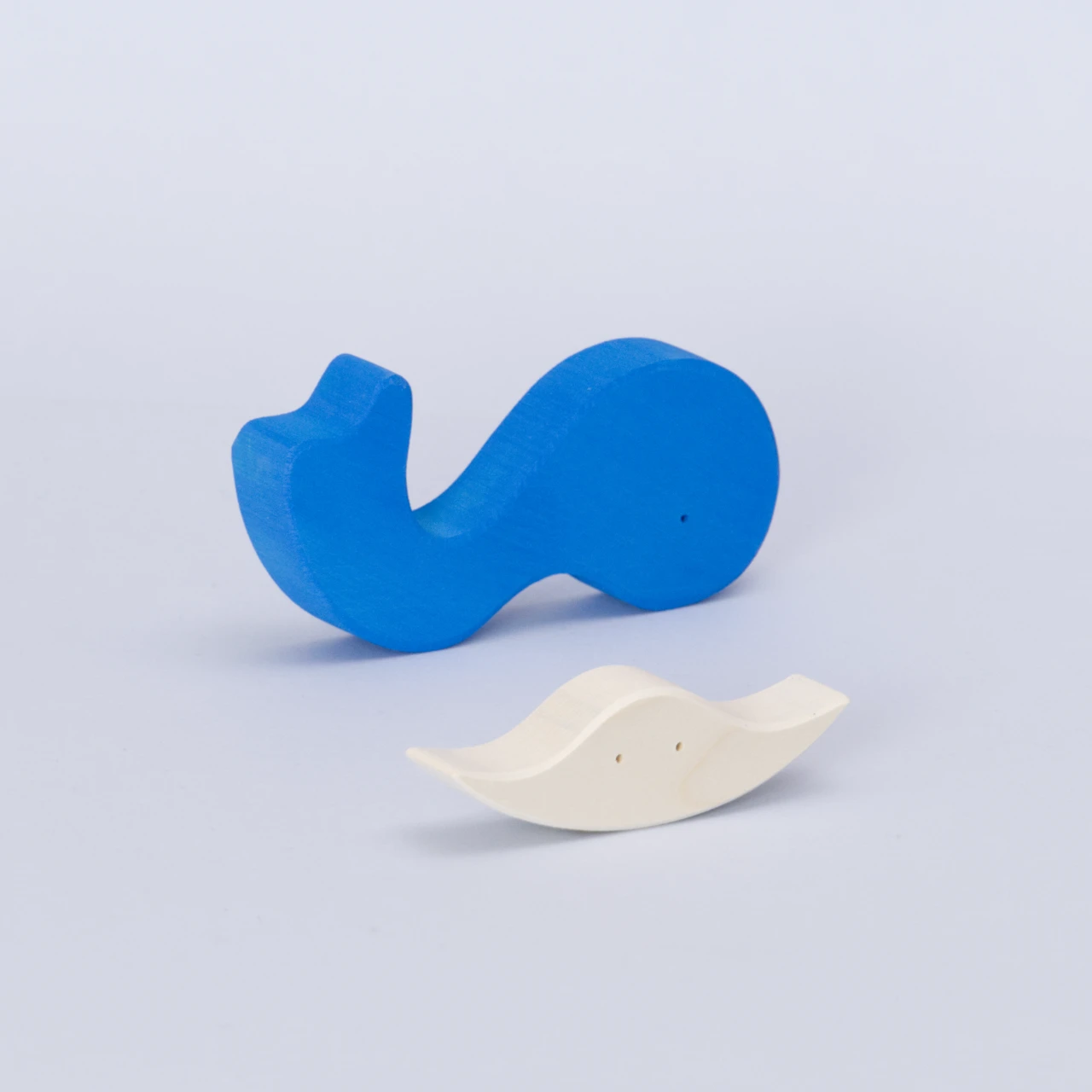 Das zweiteilige Wal Puzzle aus Holz von Goki Evolution mit dem Namen. Als der Wal einen Freund fand. Die Puzzleteile sind separiert und das größere Teil liegt im Hintergrund es ist der Körper eines azurblauen Wals, der die Flosse nach oben steckt. Das zweite Puzzleteil ist sein weißer Bauch und separat betrachtet sieht dieses Stück aus wie ein schwimmender Rochen von vorne, er hat zwei Augen.