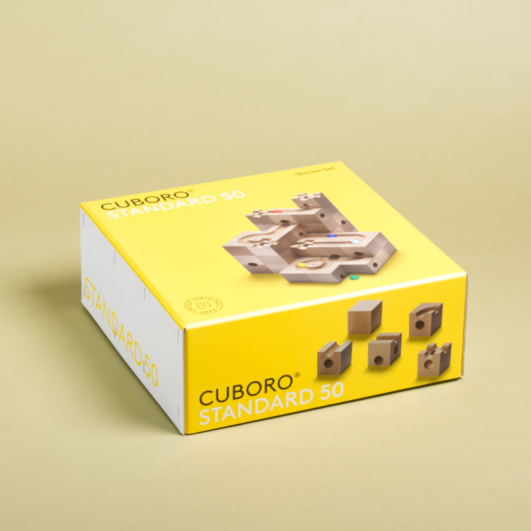 Das Standart 50 Set von Cuboro aus Buche gefertigt liegt im Produktkarton und geschlossenem Kartondeckel da.