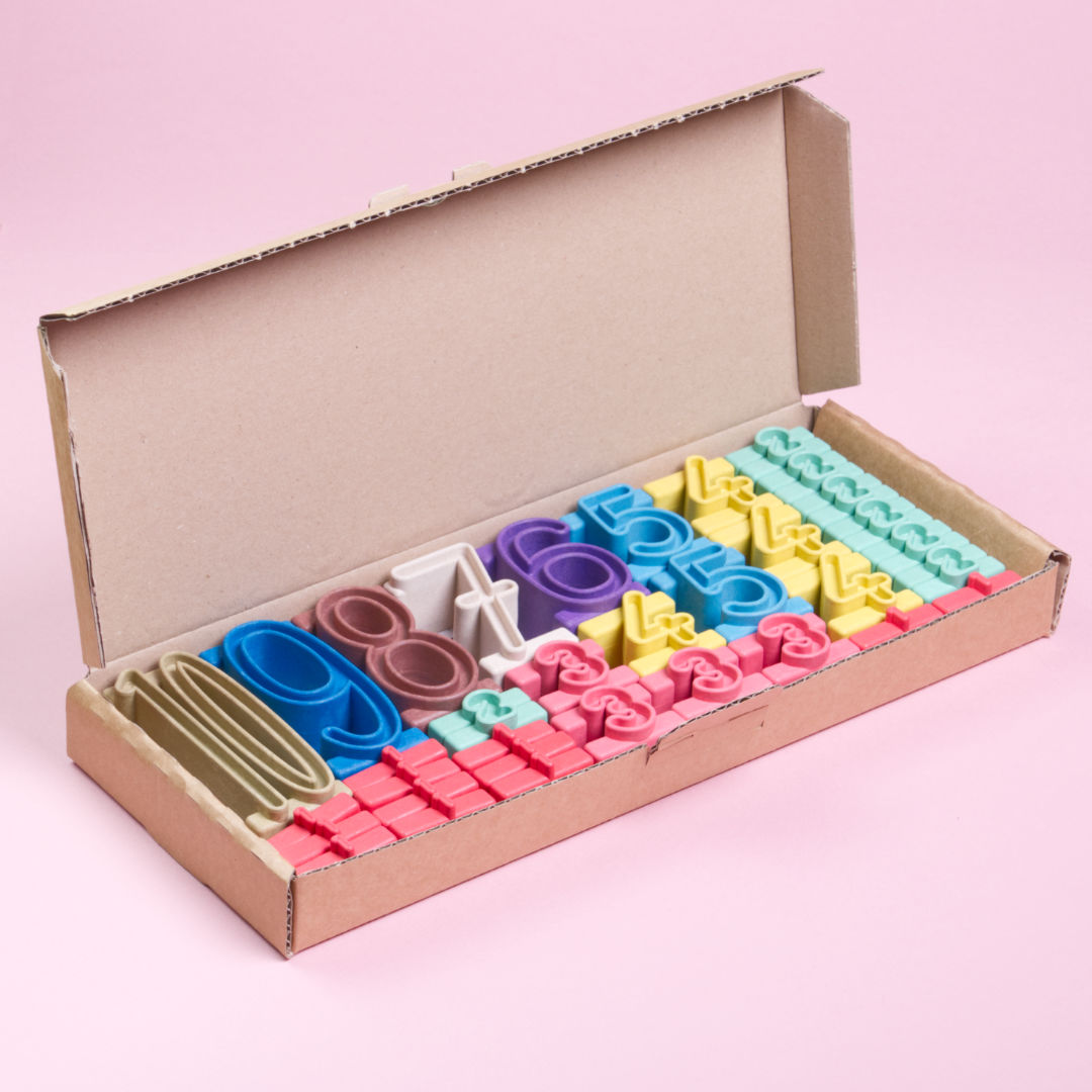 Geöffneter Karton des Produkts Stapelzahlen von Wissner. Die Stapelzahlen sind braun, beige, blau, rot, rosa, gelb, lila und grün und decken den Zahlenraum zwischen 1 und 10 ab.