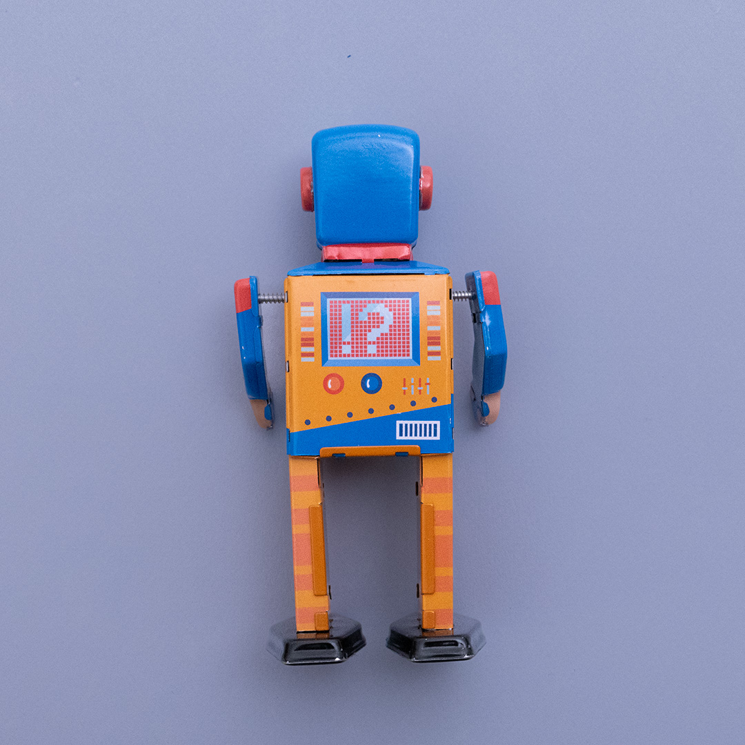 Rückansicht des Enginebot aus Blech mit orange, blau und rotem Aufdruck, hat bewegliche Arme und Beine und lässt sich mithilfe eines beiliegenden Schlüssels aufdrehen.