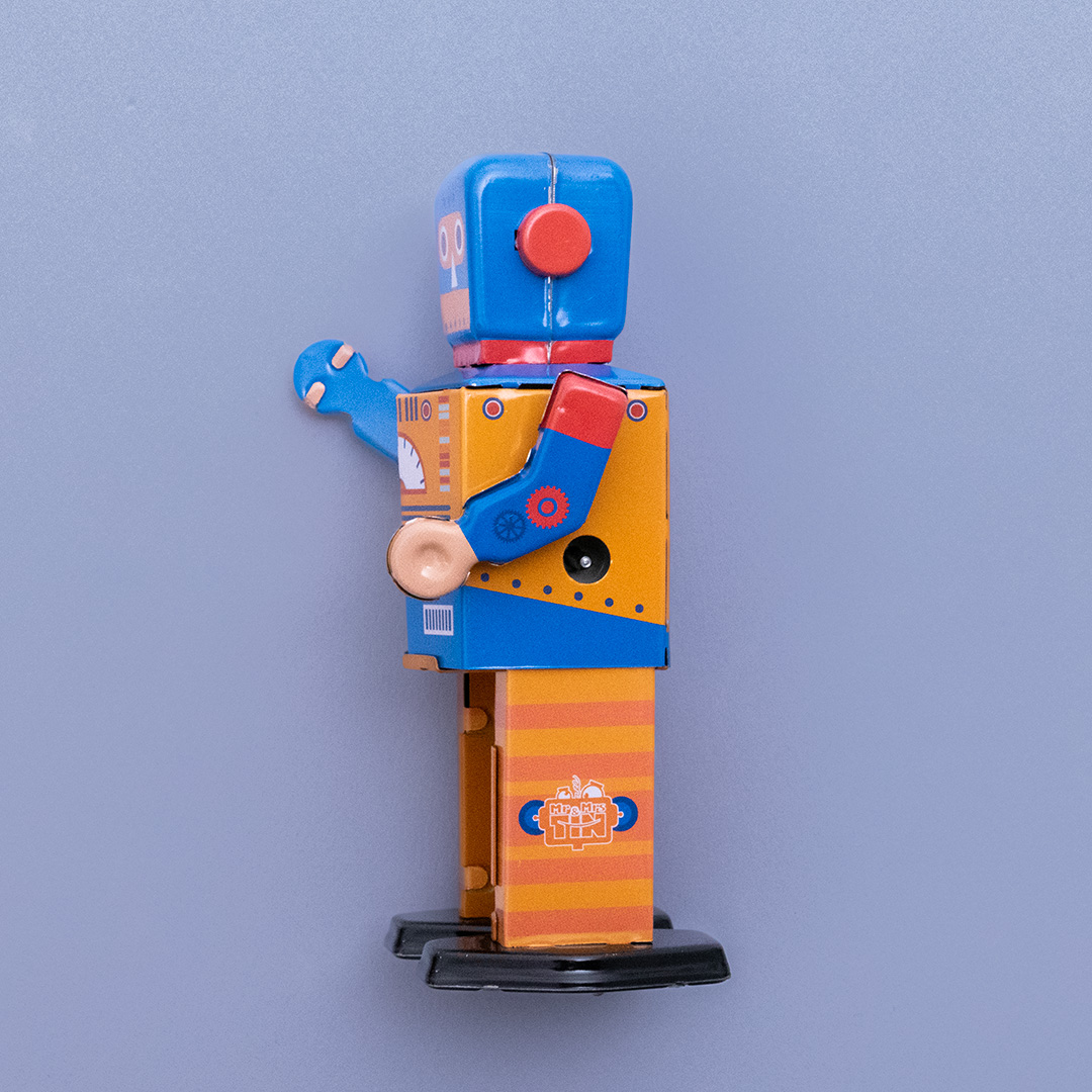 Seitenansicht des Enginebot aus Blech mit orange, blau und rotem Aufdruck, hat bewegliche Arme und Beine und lässt sich mithilfe eines beiliegenden Schlüssels aufdrehen.