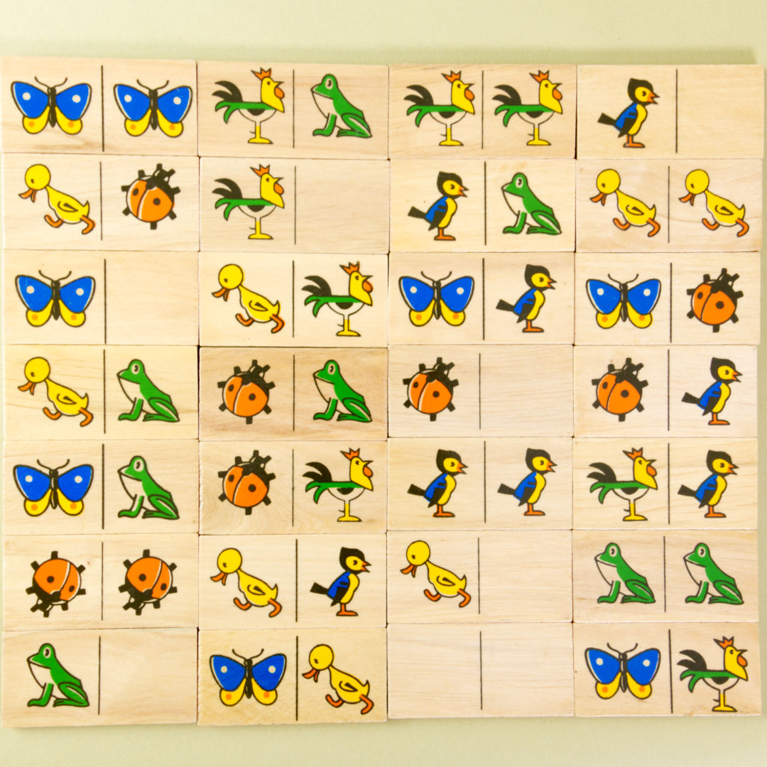 Alle Dominosteine des Spiels aneinanderliegend zur Übersicht fotografiert. Frosch, Marienkäfer, Vogel, Schmetterling, Hahn und Küken dienen als Spielmotiv.