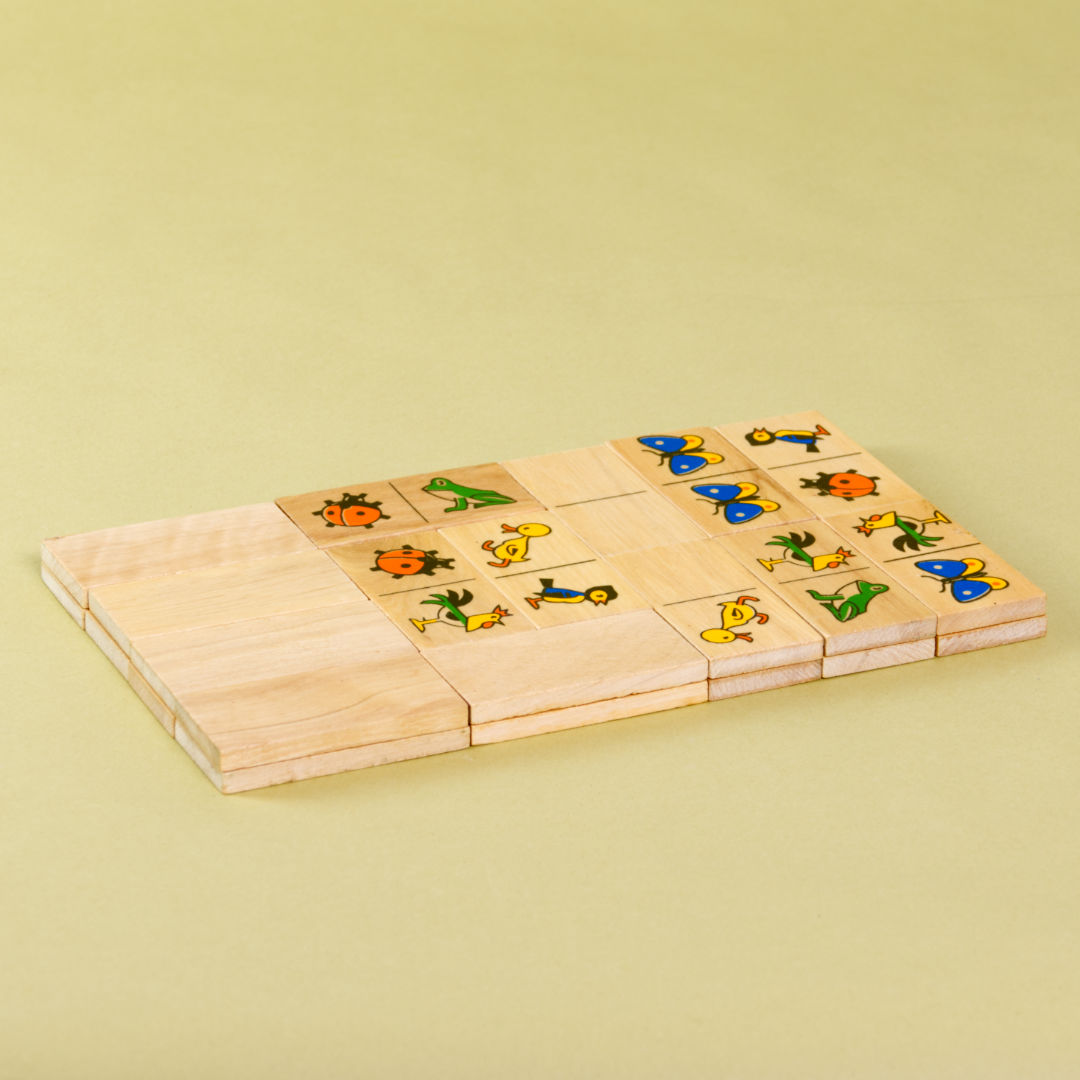Alle Dominosteine des Spiels als Block fotografiert. Frosch, Marienkäfer, Vogel, Schmetterling, Hahn und Küken dienen als Spielmotiv.