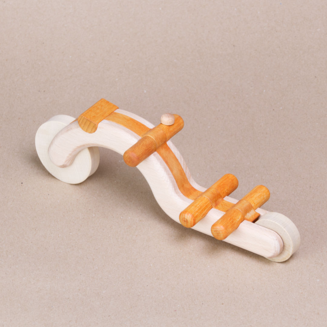 Seitenansicht eines in orangefarben gehaltenen Fahrrads aus PEFC-zertifiziertem Buchenholz mit zwei Rädern, einem Lenker mit linksseitiger Klingel, Sattel und abnehmbarem Trägerkorb. Die Räder sind rollbar