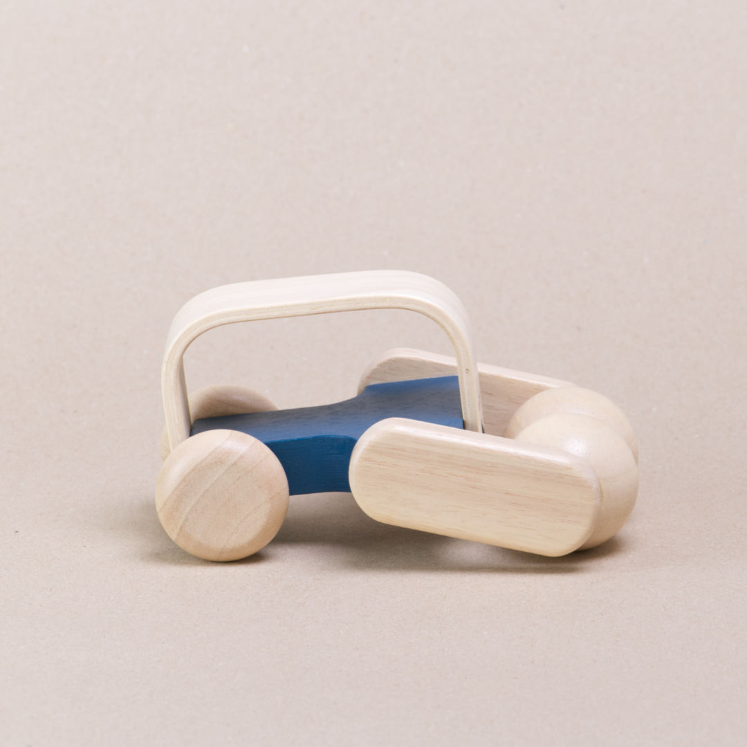 Seitenansicht des Massagerollers aus Holz von Plan Toys. Der Zentralkorpus ist blau, der erst in Naturfarben. Die Vorder- und Hinterrollen sind beweglich. Zum besseren handeln besitzt der Massageroller einen Griff.