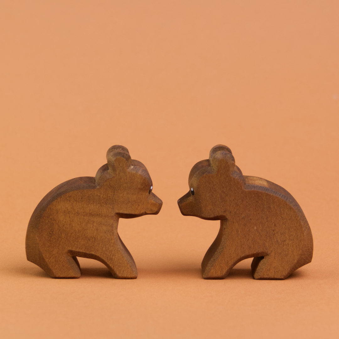 Zwei kleine Bären aus Holz sitzen sich gegenüber und schauen sich an. Sie machen einen runden Rücken und sind von der Marke Ostheimer.