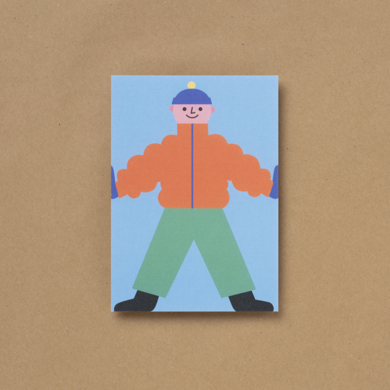 Die von Susann Stefanizen gestaltete Postkarte, mit dem Titel "Happy Kids X" ist in der Draufsicht zu sehen. Es ist ein Junge mit einer orangefarbenen, dicken Jacke, dunkelblauen Handschuhen sowie einer Mütze und einer dunkelgrünen, langen Hose an, zu sehen. Er hat schwarze Schuhe an und lächelt, seine beiden Arme hält er gestreckt an die Außenseiten der Karte. Der Hintergrund ist hellblau eingefärbt.