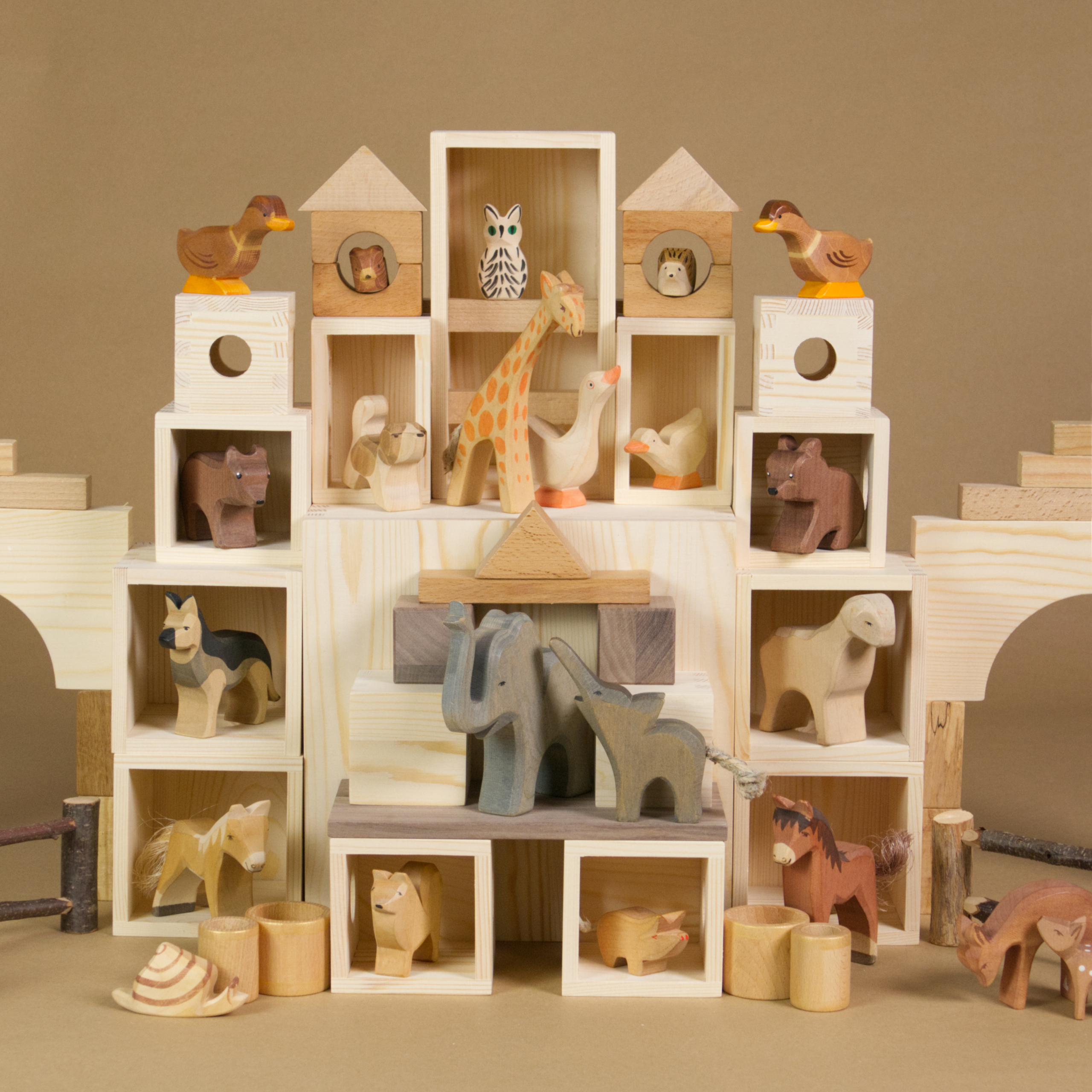 Eine MATZBOX-Idee: Die Bauteile der Matzbox sind symmetrisch angeordnet zu einem großen Spielhaus, in dem Holztiere von Ostheimer wohnen. Die Tiere haben alle ein Zimmer. Die Bauelemente, Holzkisten und Bausteine sind mit anderen Bauklötzen kombiniert.
