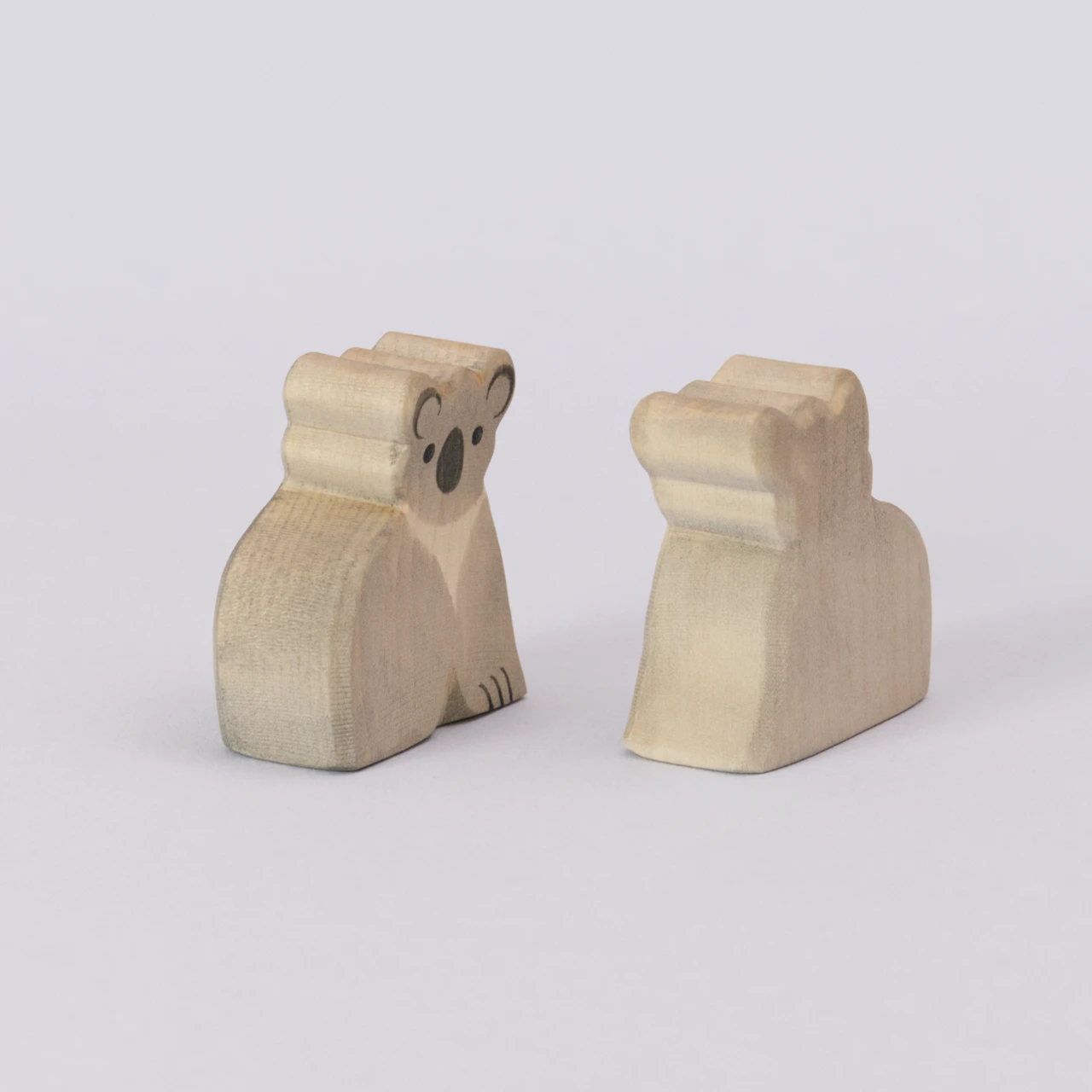 Zwei Koalas von Ostheimer, aus Holz zum Spielen, in den Farben grau und schwarz für das Gesicht. Die Koala werden seitlich zueinander gedreht gezeigt.